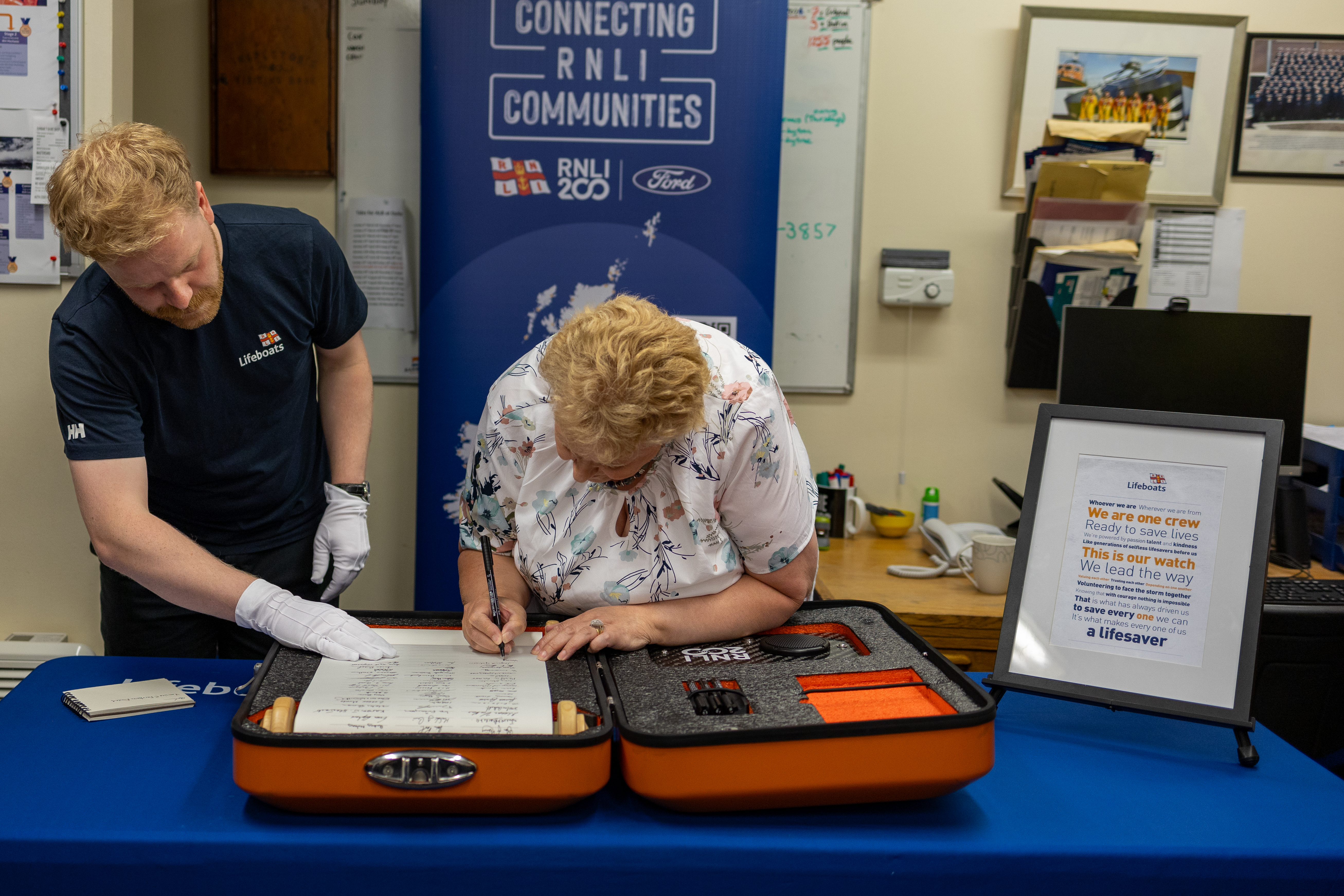 Woman signs scroll, while man watches