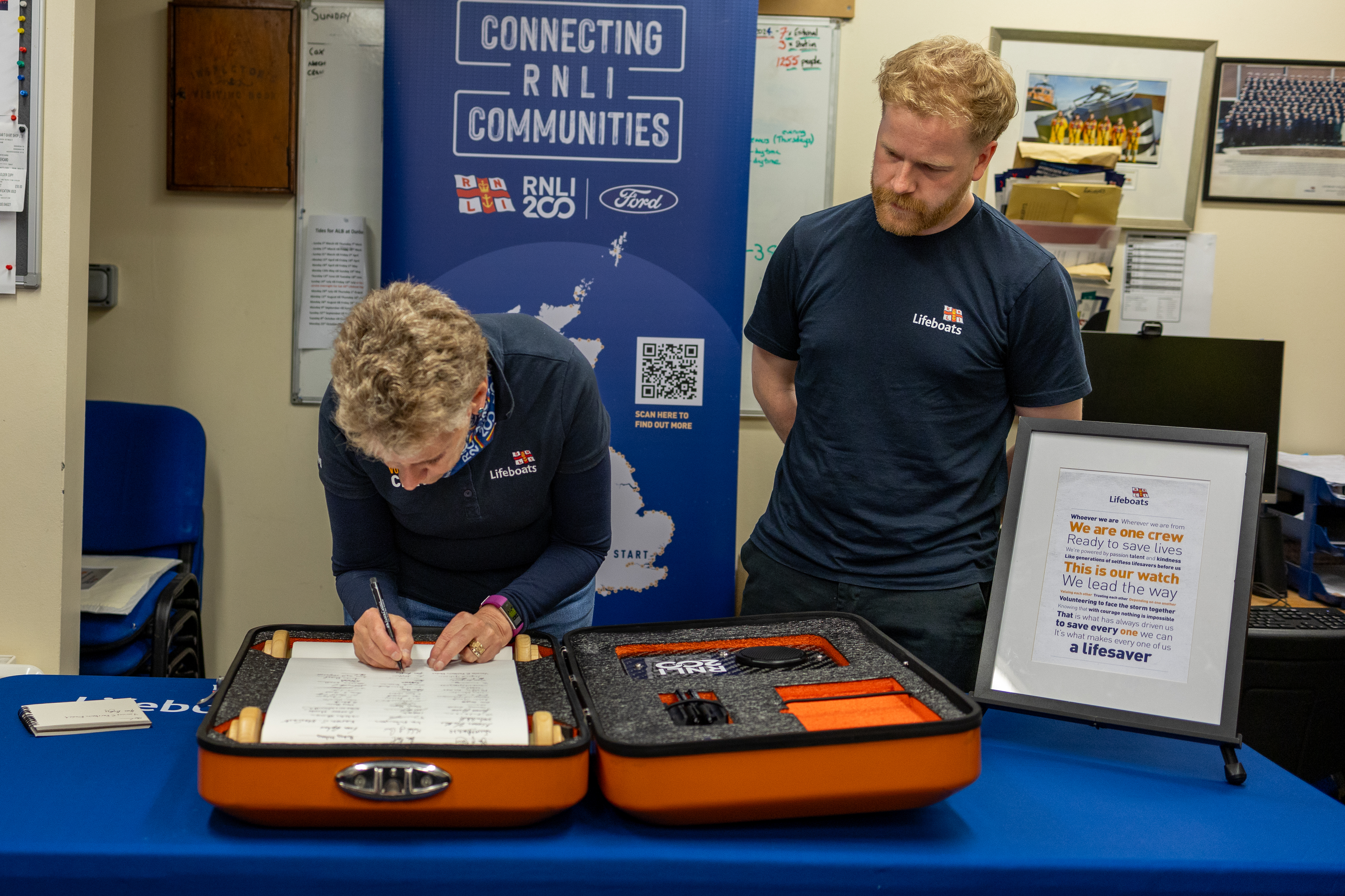 Woman signs scroll, while man watches