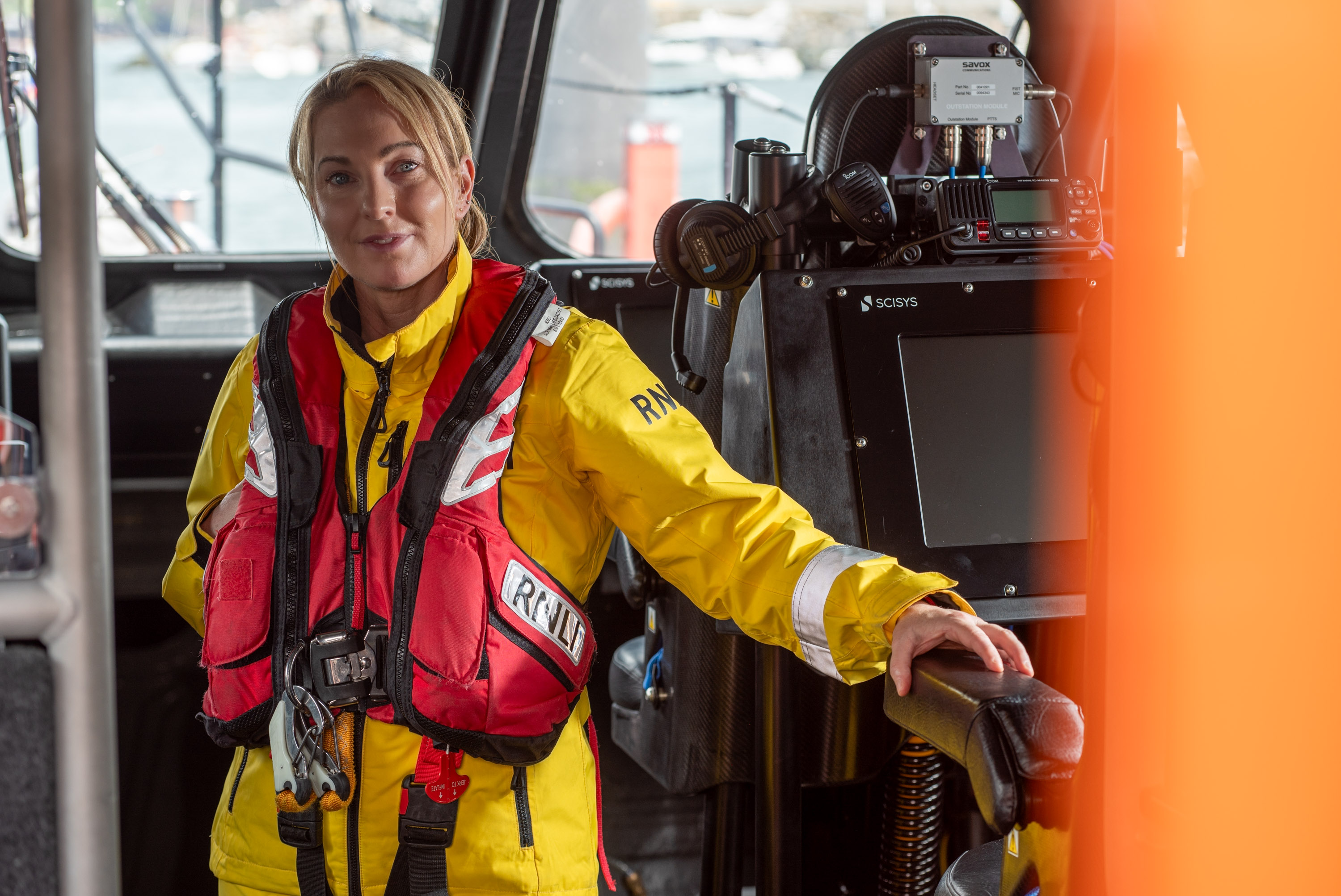 Photo of Susan in yellow RNLI PPE in the wheelhouse of an lifeboat