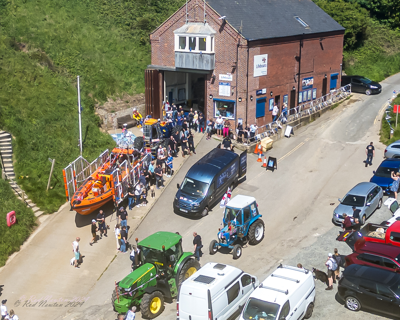 Aerial photo of the slipway and lifeboat station with E-Transit, escorting tractors and Atlantic 85 Lifeboat. A small crowd of people looking on.