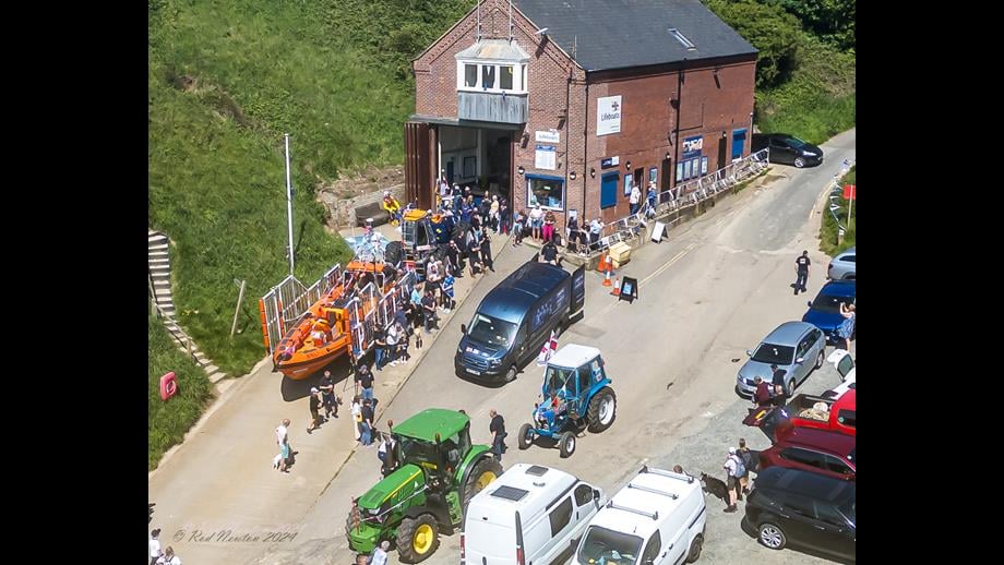 RNLI200 Scroll delivered to Flamborough Lifeboat Station Aerial photo of the slipway and lifeboat station with E-Transit, escorting tractors and Atlantic 85 Lifeboat. A small crowd of people looking on.