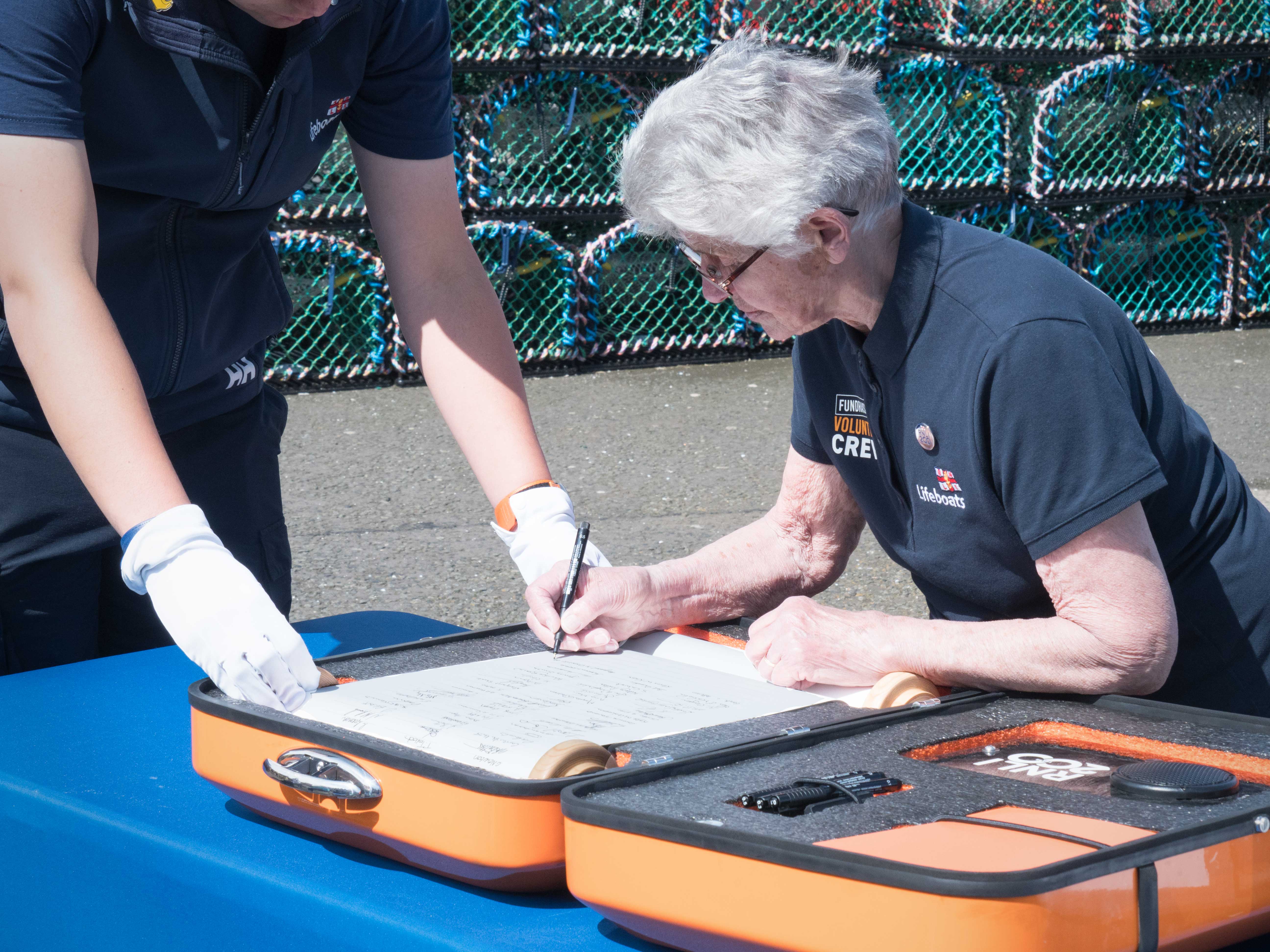 Margaret Driscoll, of RNLI Burnmouth &amp; Eyemouth Fundraising Group, signs the 'Connecting our Communities' scroll
