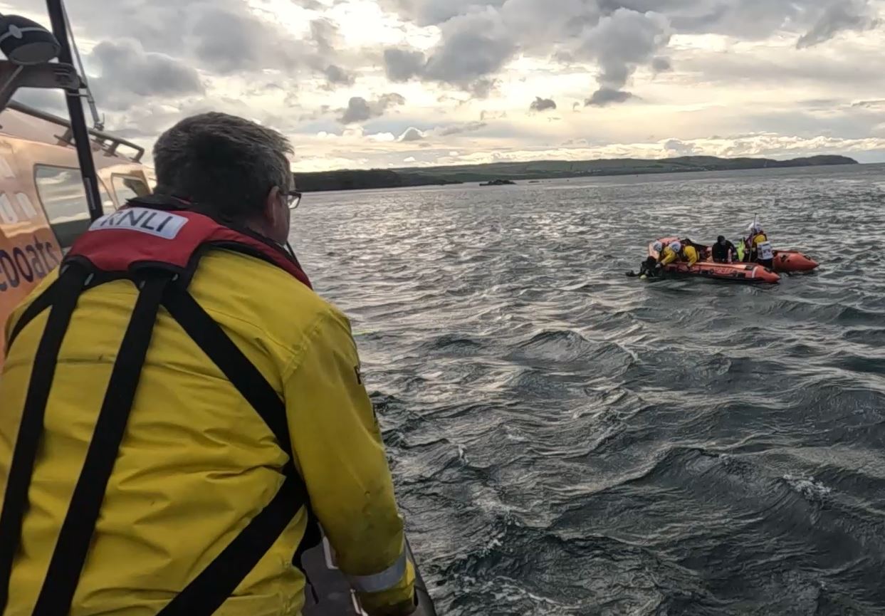 Two divers are helped aboard Eyemouth RNLI inshore lifeboat, watched over by volunteers on the all-weather lifeboat