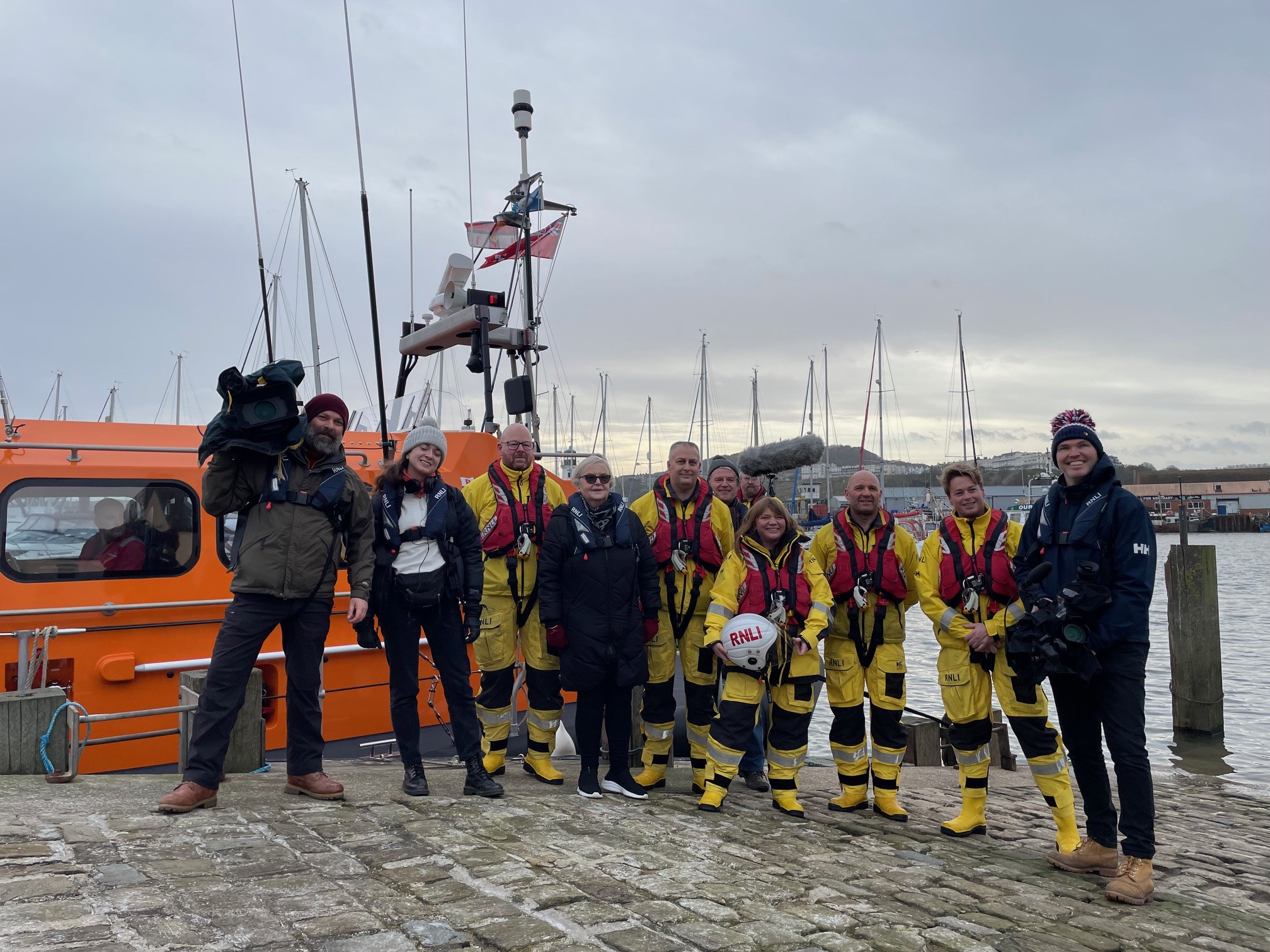 RNLI Crew in yellow with film crew andtheir cameras