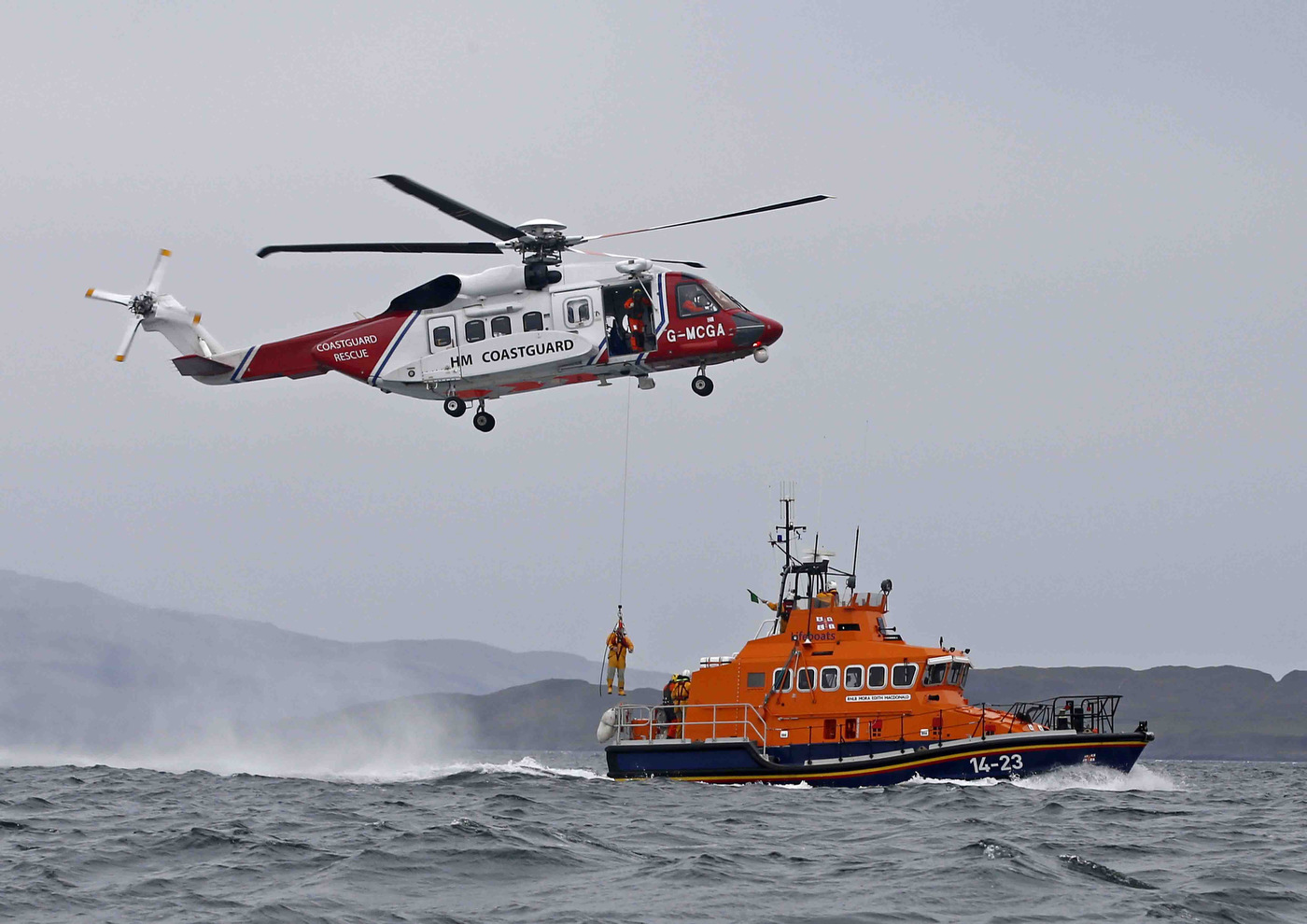A Coastguard helicopter hovers over the wake of the moving lifeboat