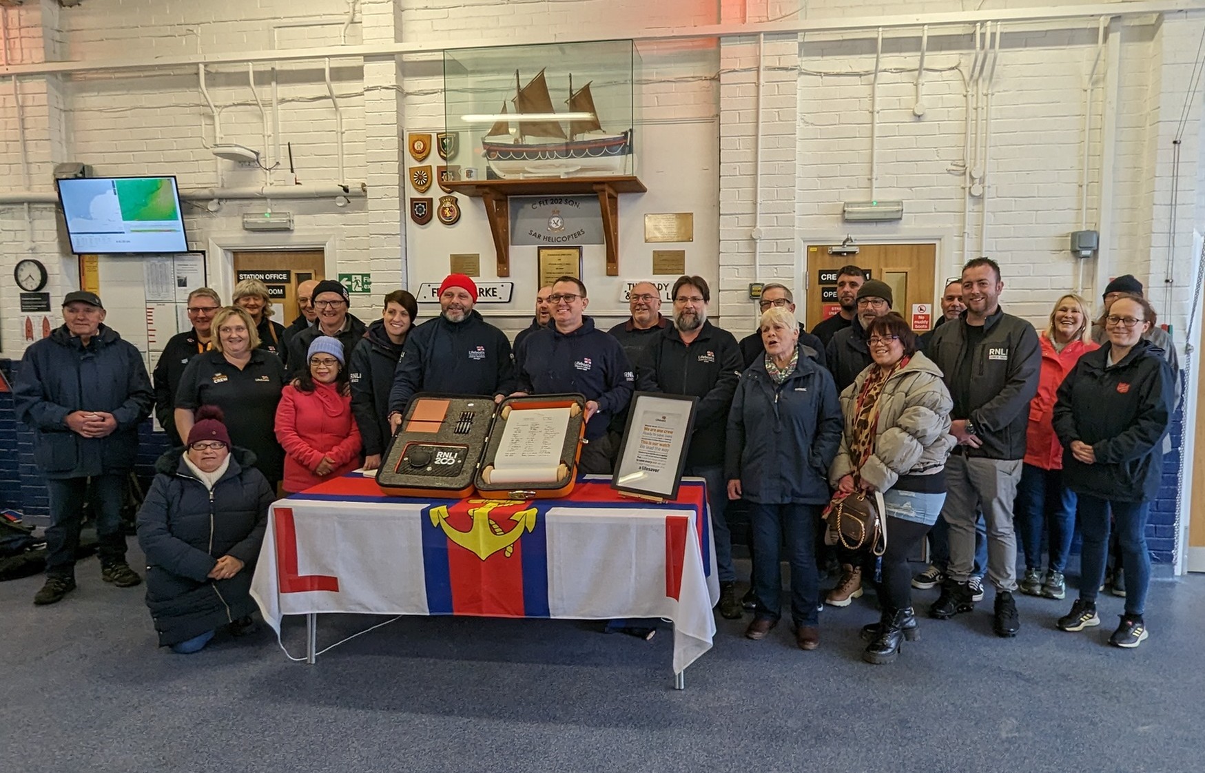 A large group of crew members and supporters at Littlestone with the scroll 