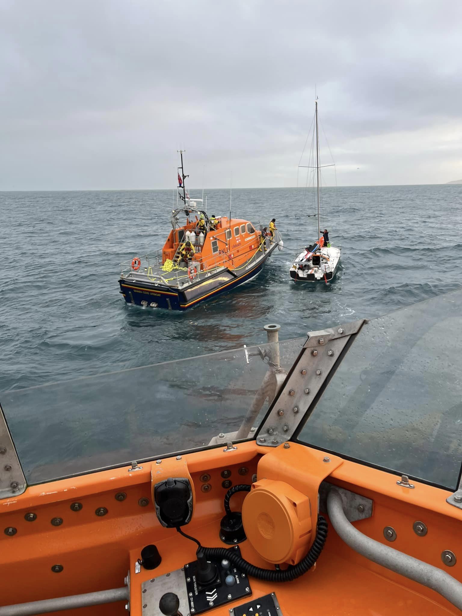 Shows two lifeboats at work on a yacht rescue