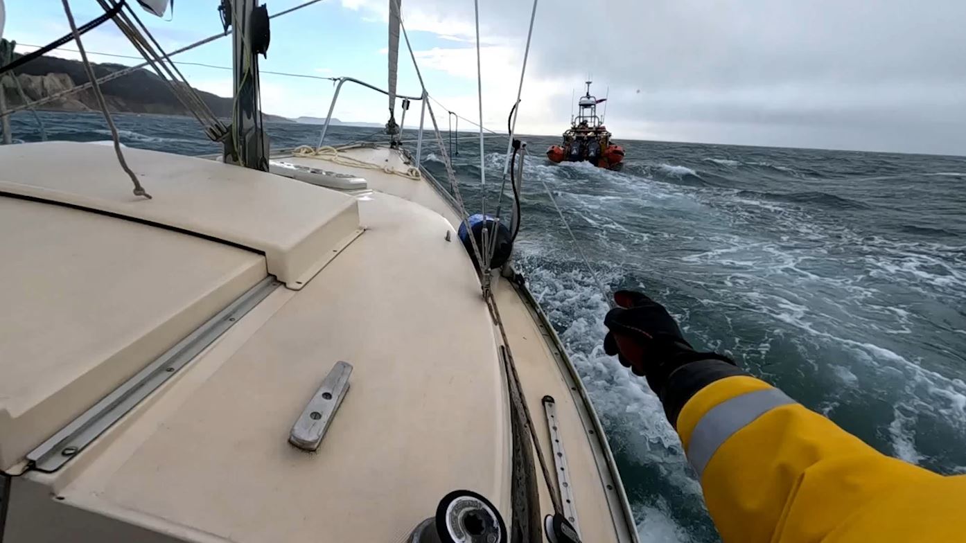 Photo shows casualty yacht under tow by Lyme Regis inshore lifeboat