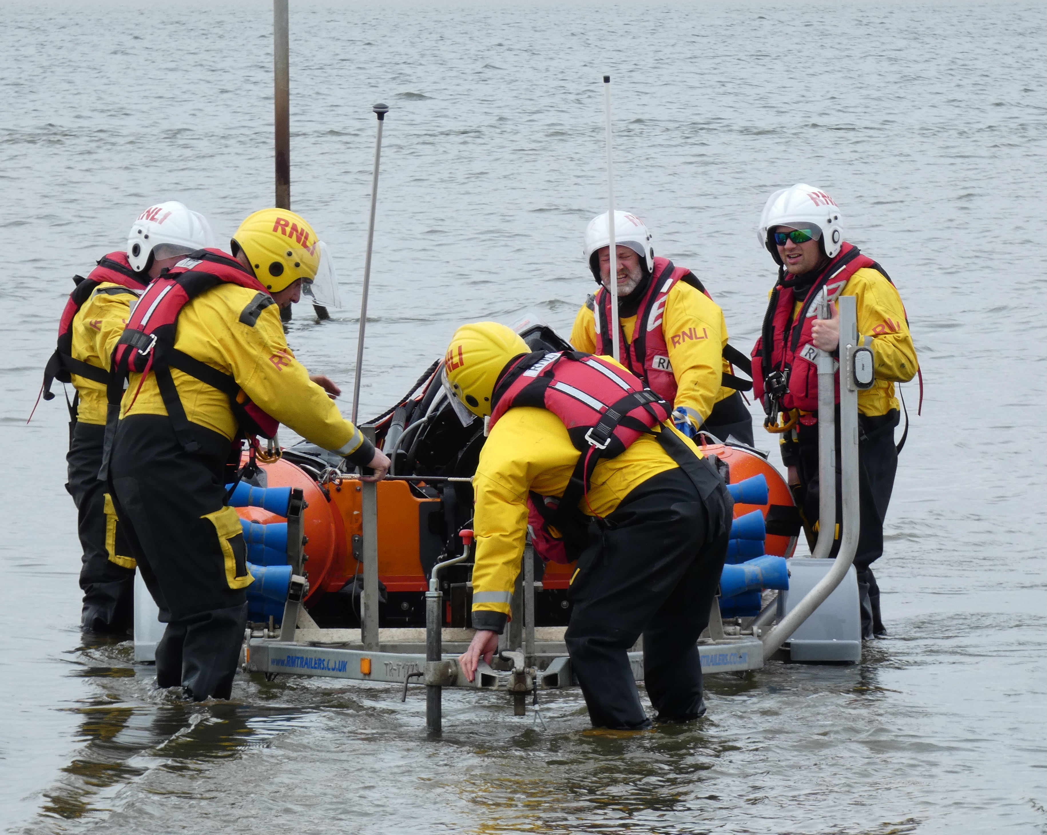 Five Lifeboat Crew members pull an Inshore Lifeboat back onto her carriage