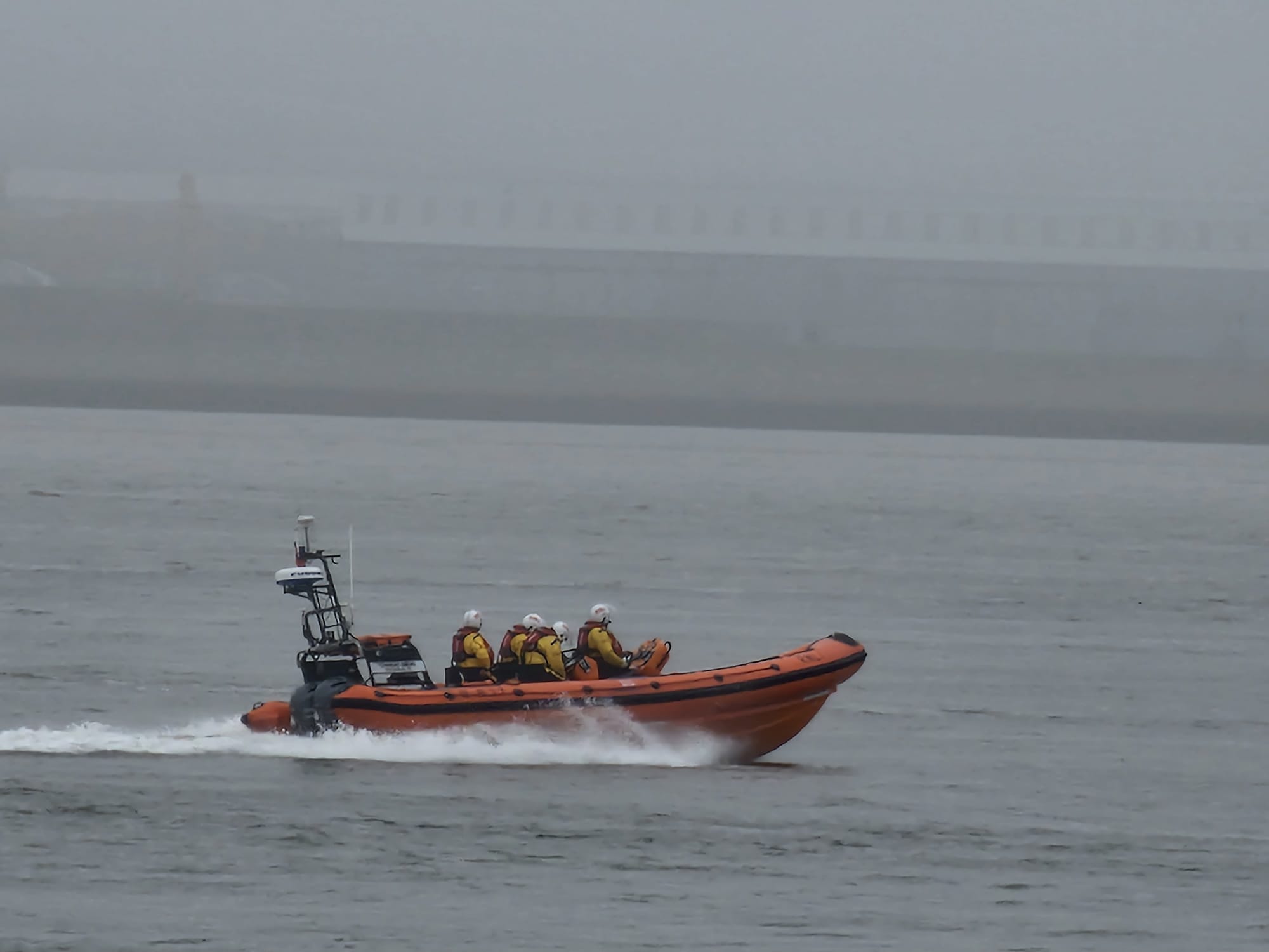 New Brighton RNLI's Atlantic-85 lifeboat is seen travelling at speed on a foggy river.