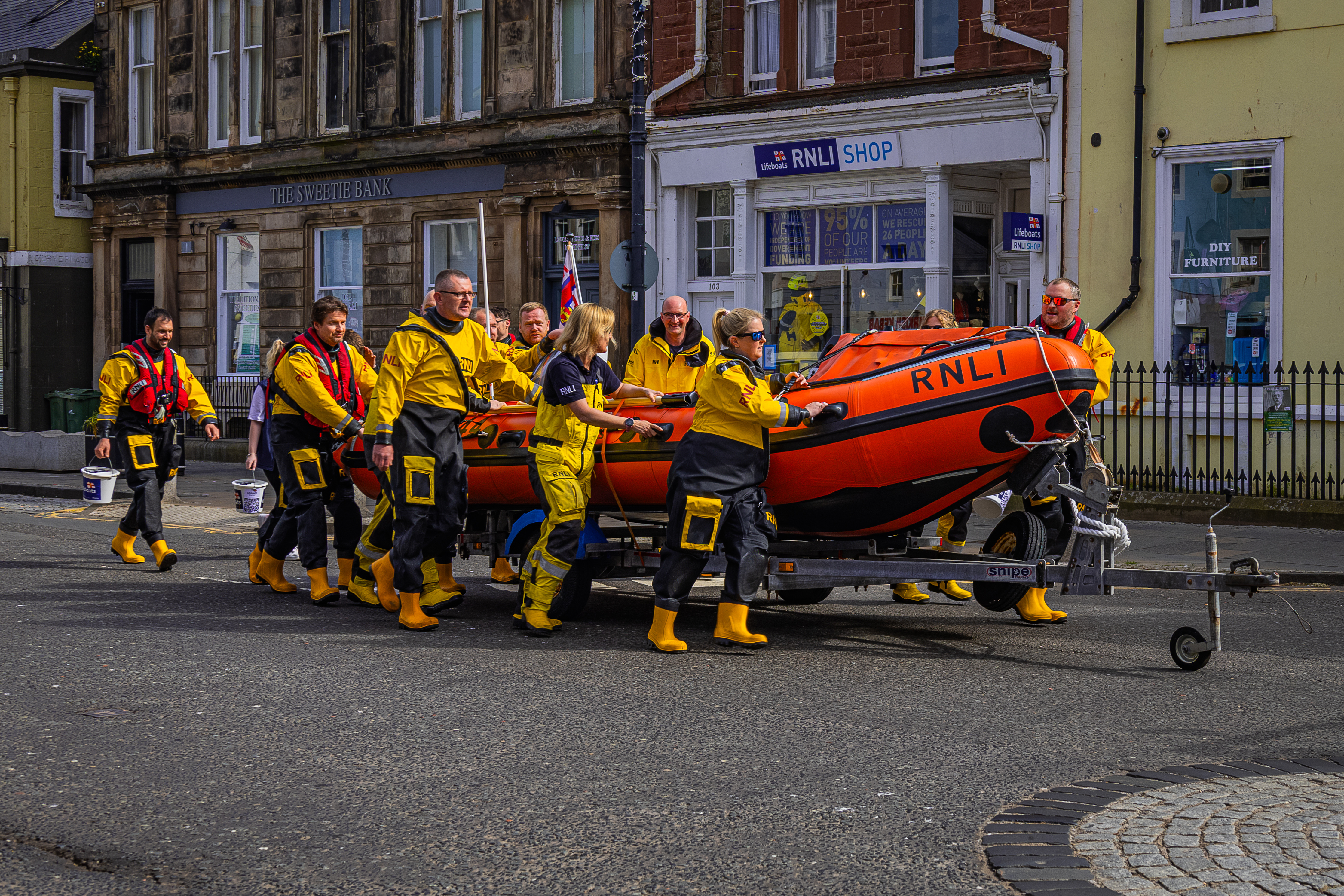 People in lifeboat gear push inflatable RIB on trailer.