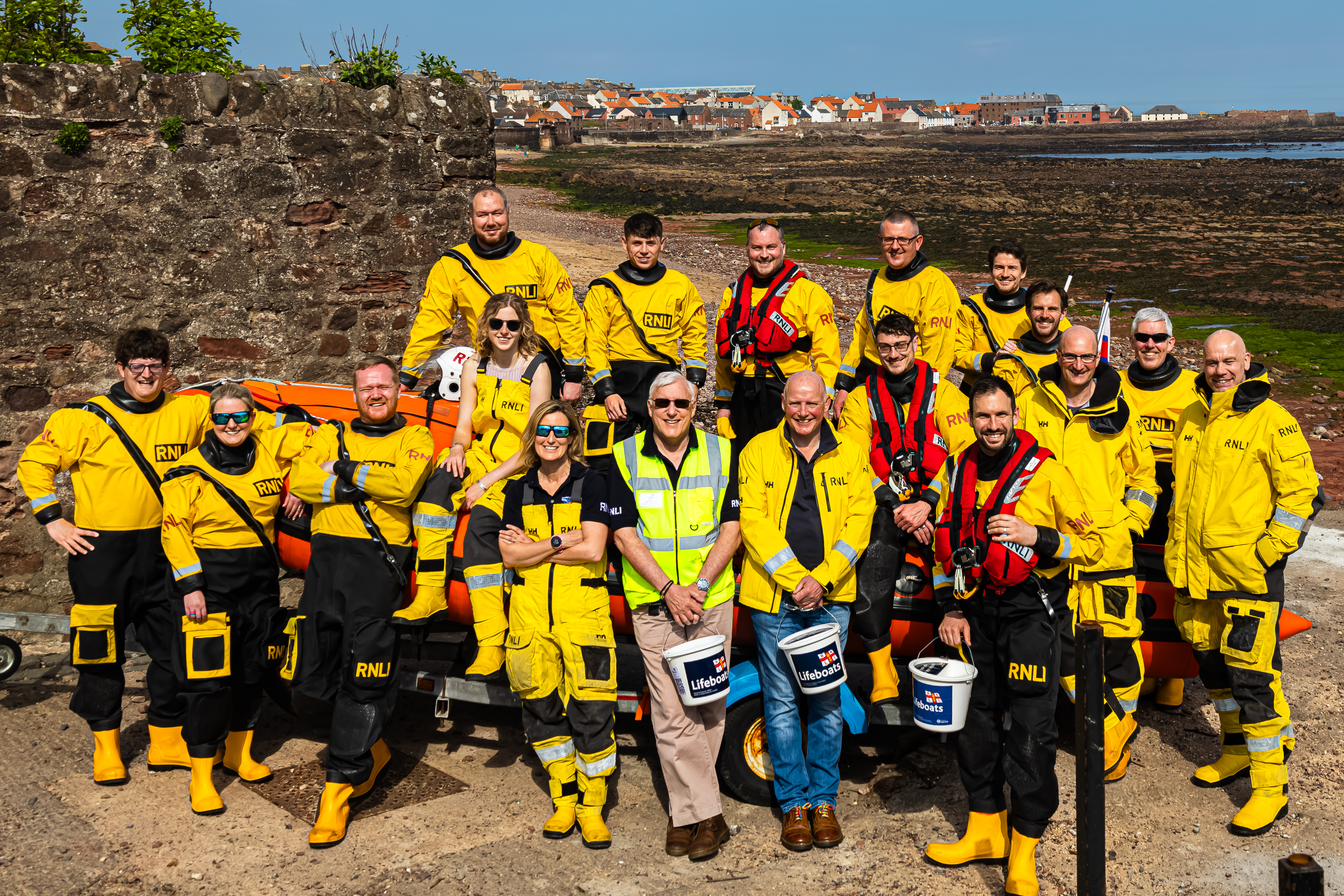 Group photo of volunteers next to lifeboat on beach.