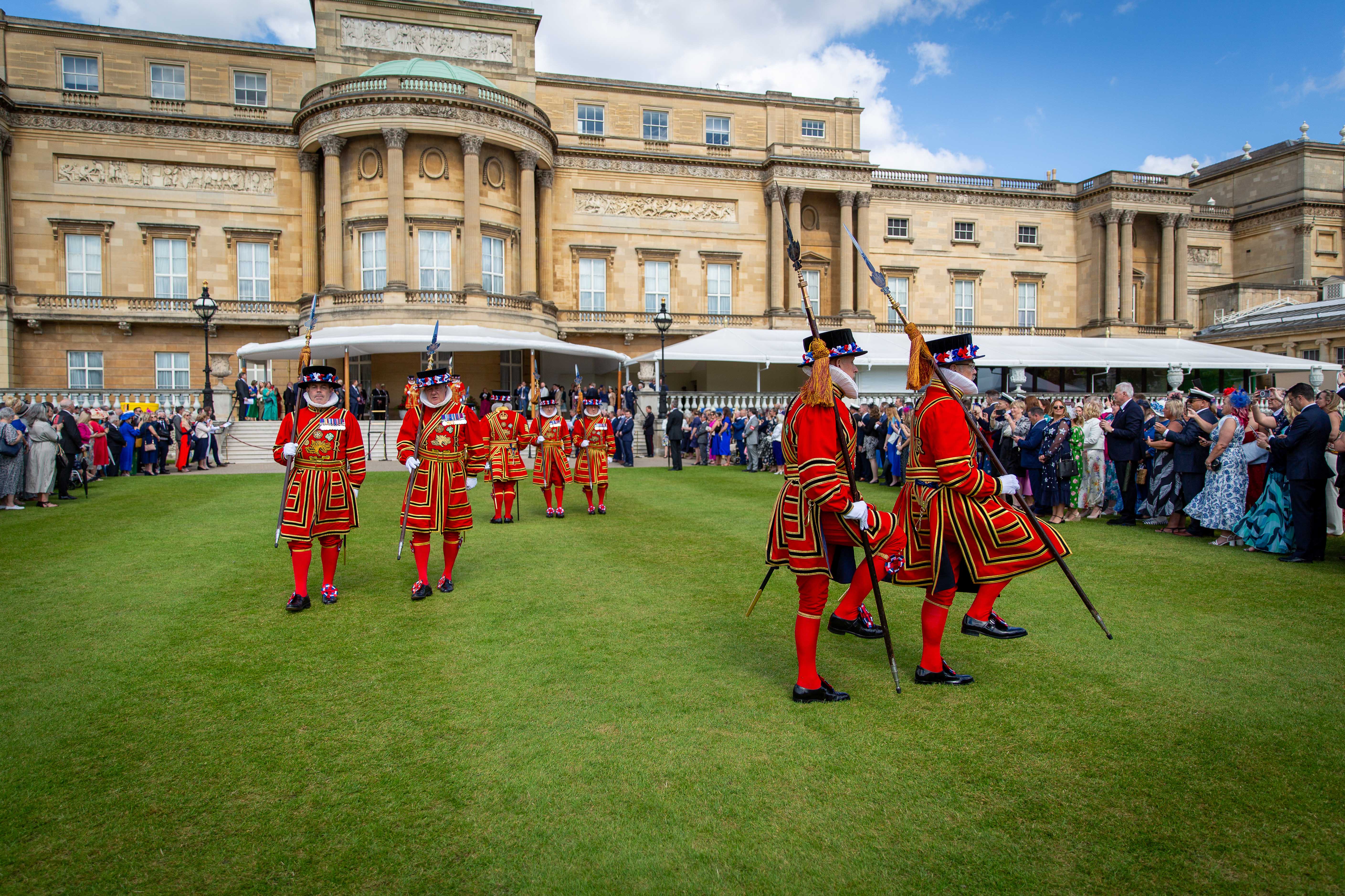 The Royal Guard march down the lawn away from Buckingham Palace.