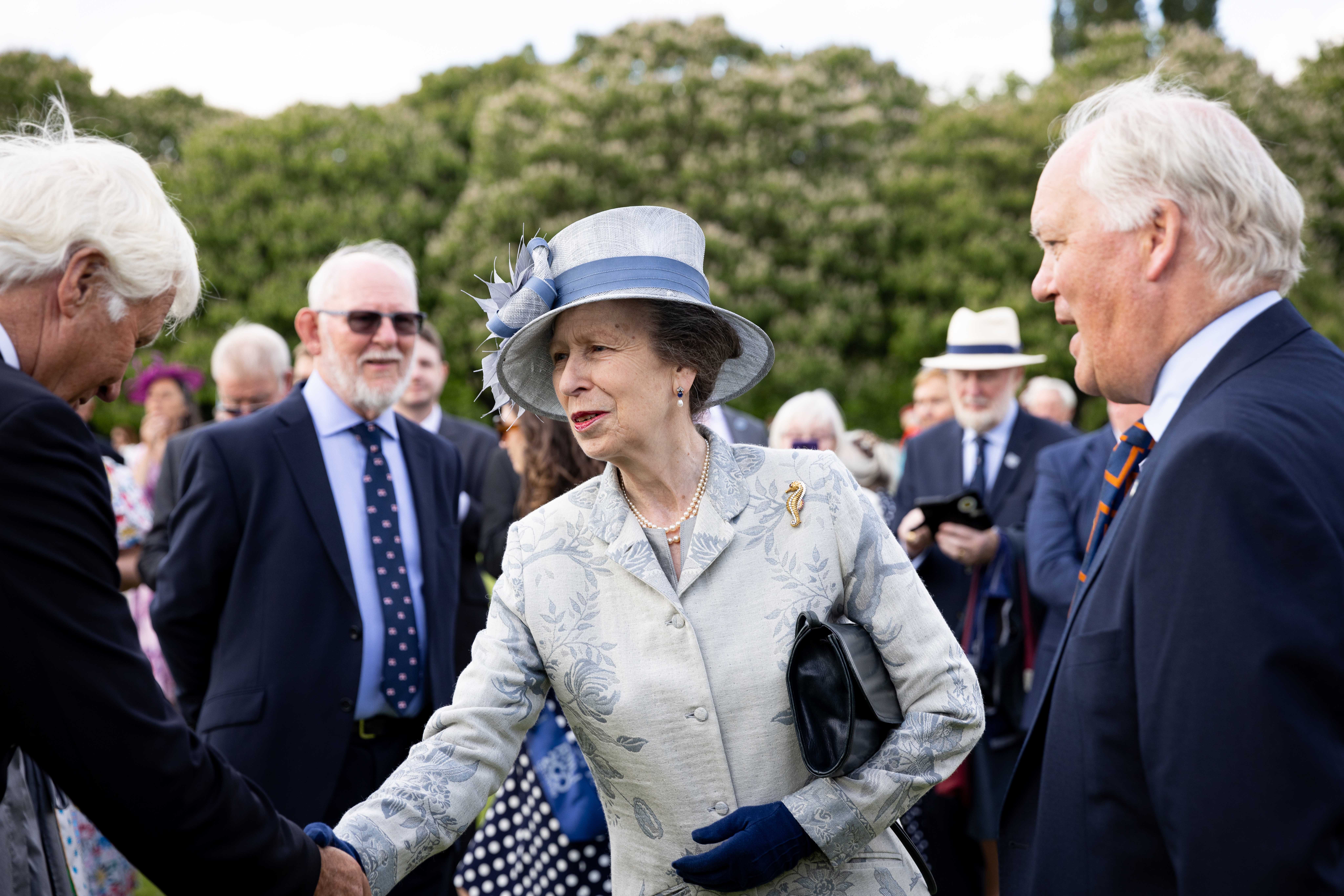 Centre of the photo is HRH Princess Ann, hand extended mid-handshake with a guest. Others watch on nearby.