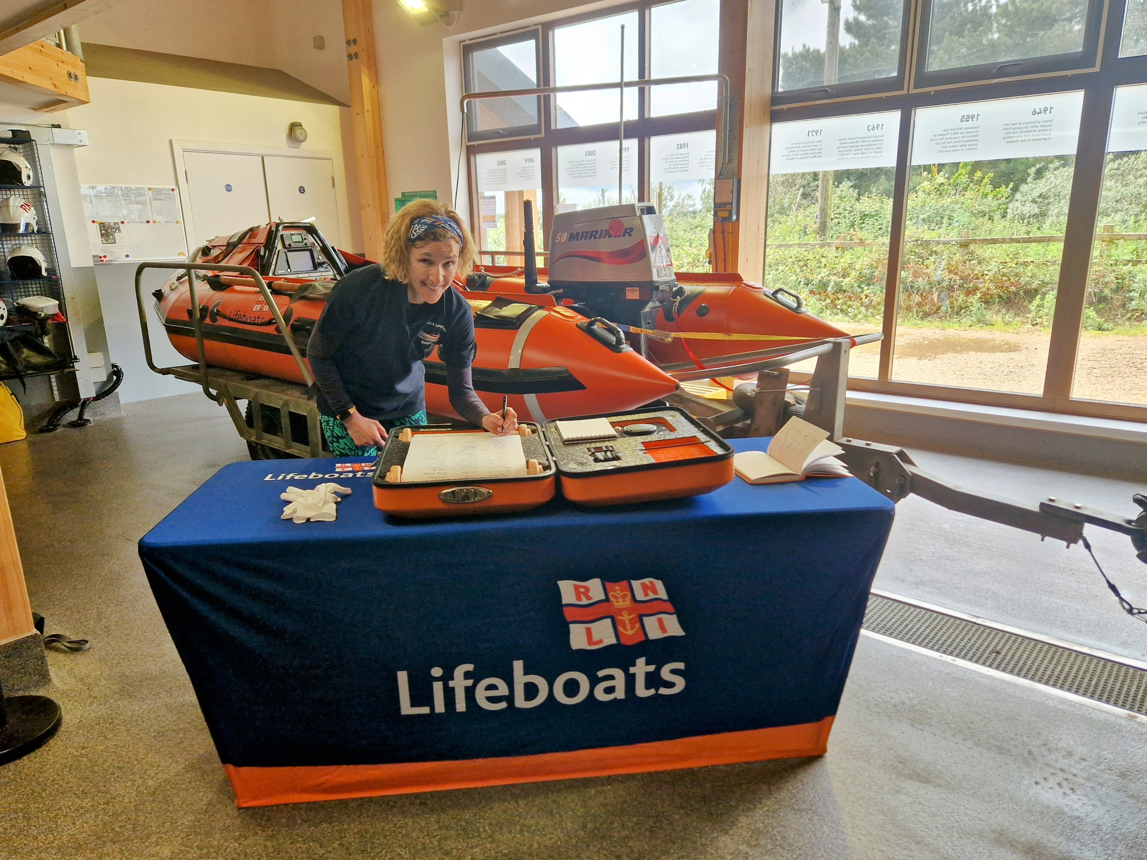 Crew member signing the scroll with D-Class inshore lifeboat in background