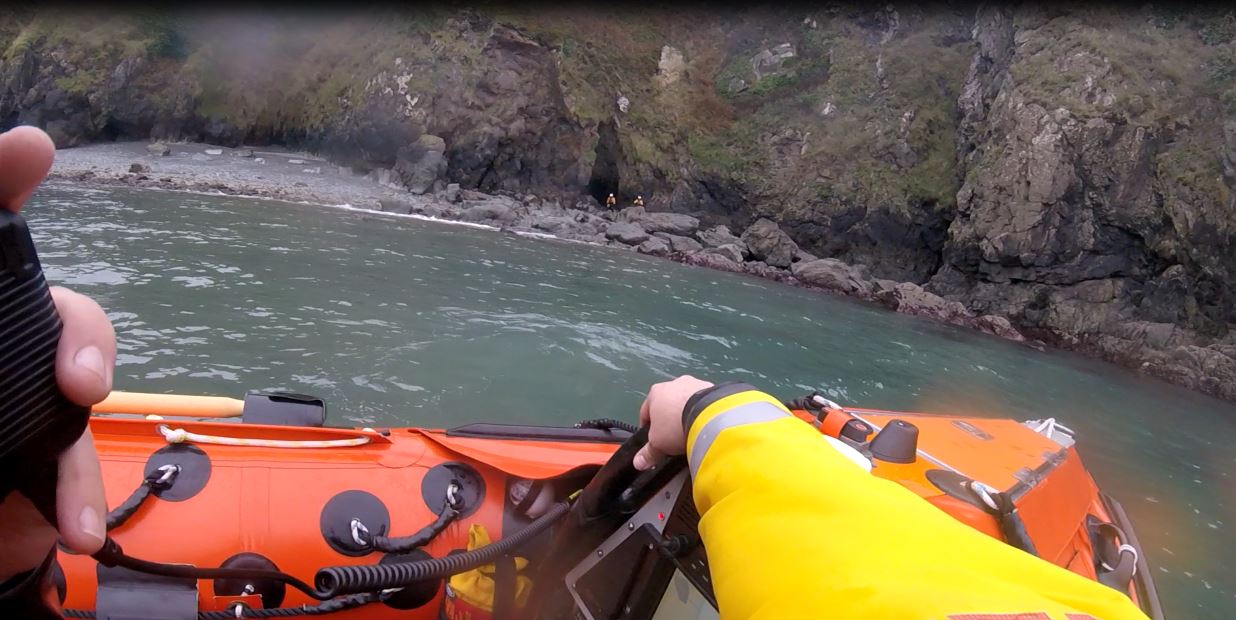 Inshore lifeboat crew communicating with colleagues ashore following investigation of unrelated debris in a cave.
