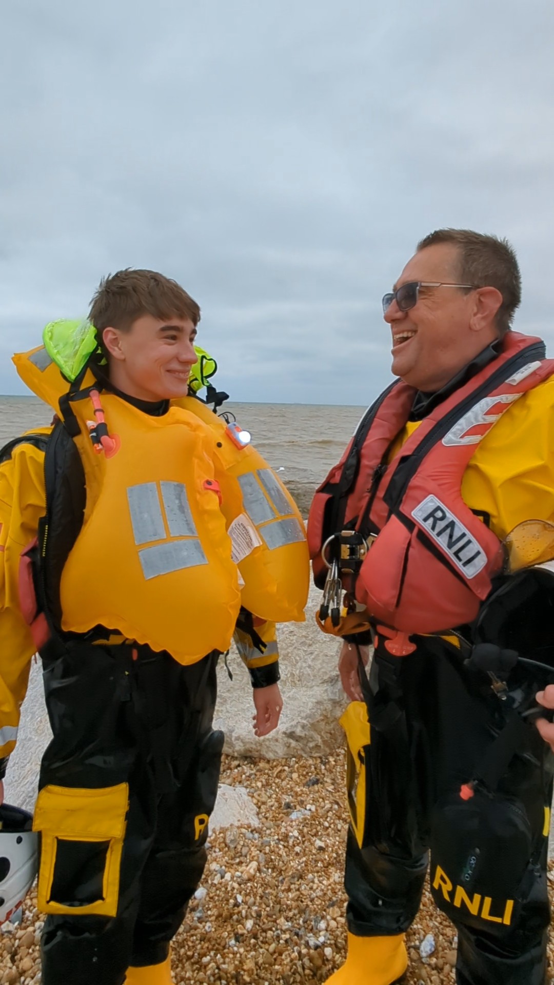 Father and son, Peter and Samuel Leigh in yellow and black RNLI kit share a joke after Sam's first trip in the lifeboat with his dad
