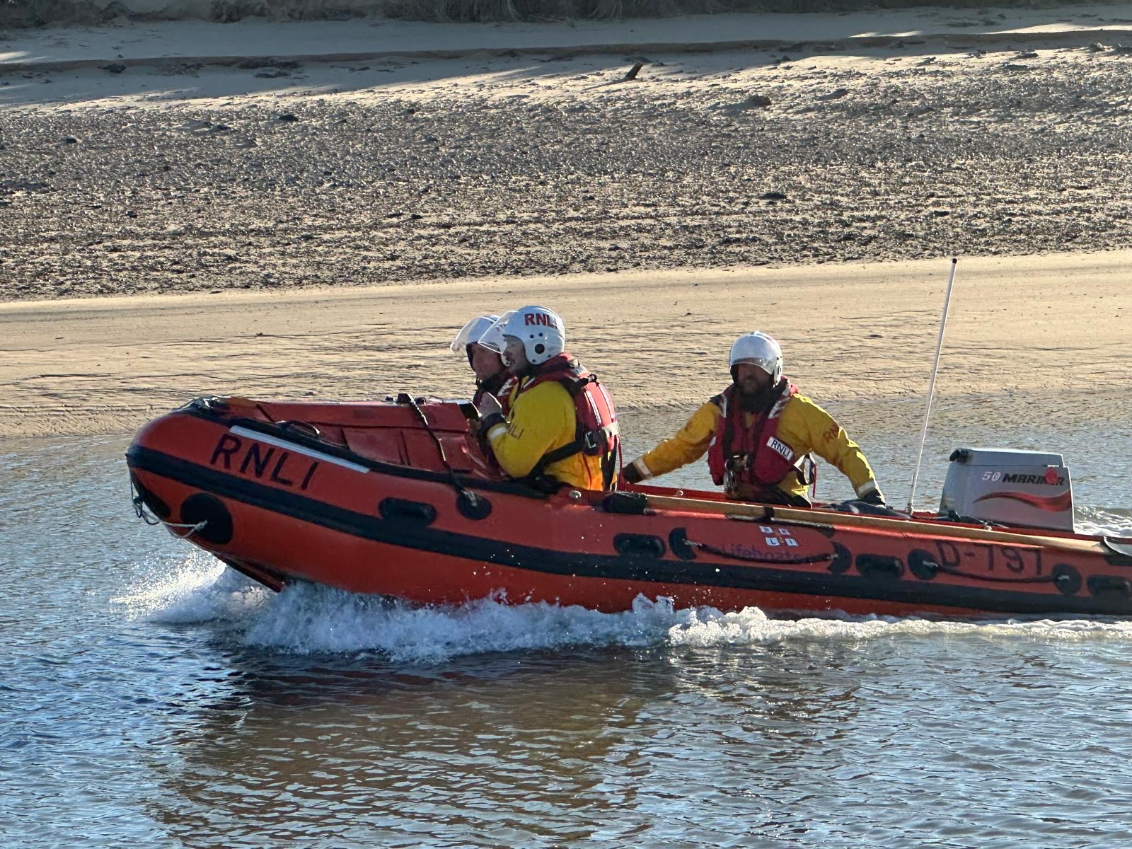 Wells RNLI inshore lifeboat launches to assist two people cut off by the tide. Crew of three volunteers on board.
