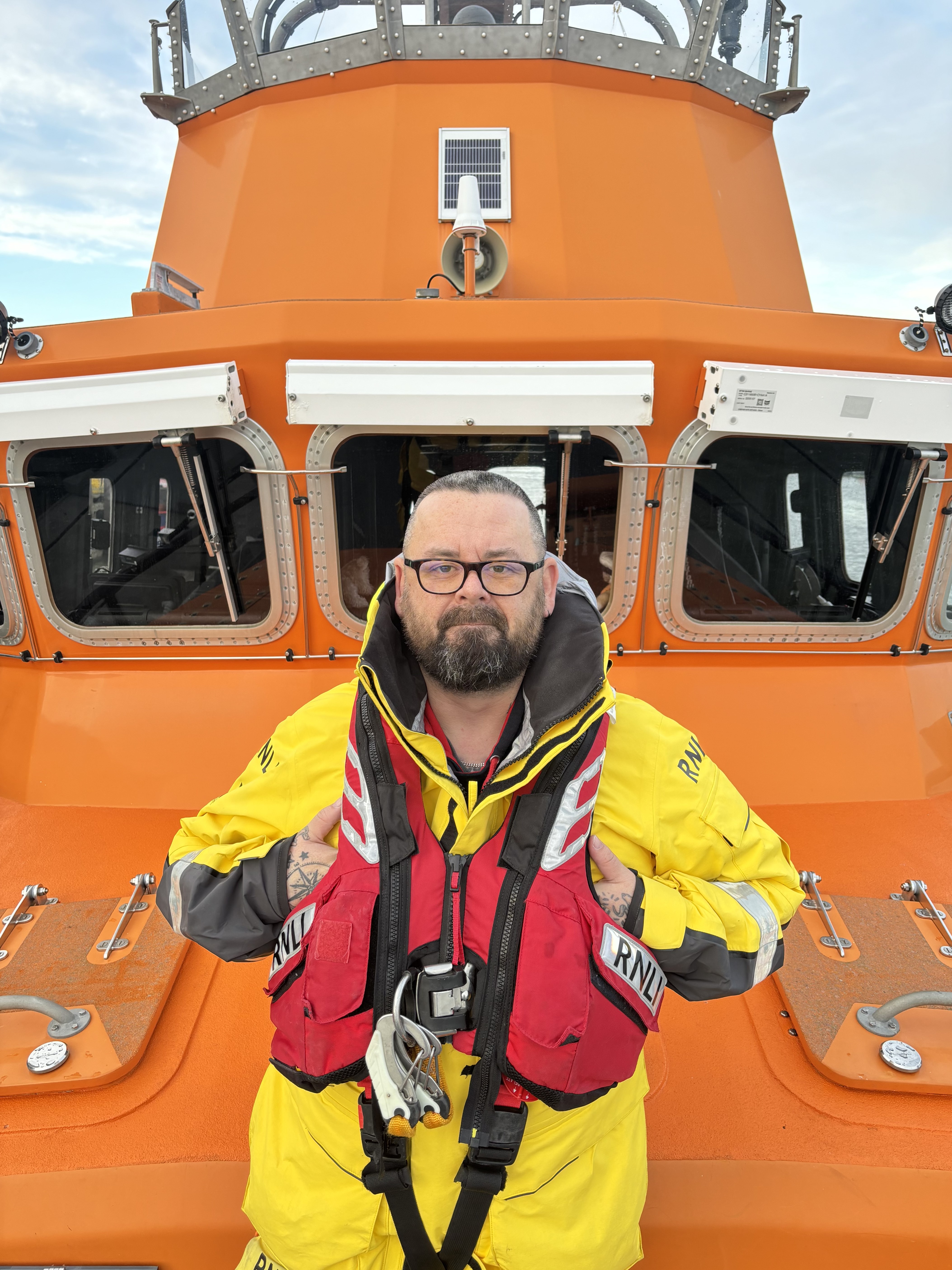 Volunteer lifeboat crew member Rich White standing on Newhaven RNLI's Severn Class all-weather lifeboat