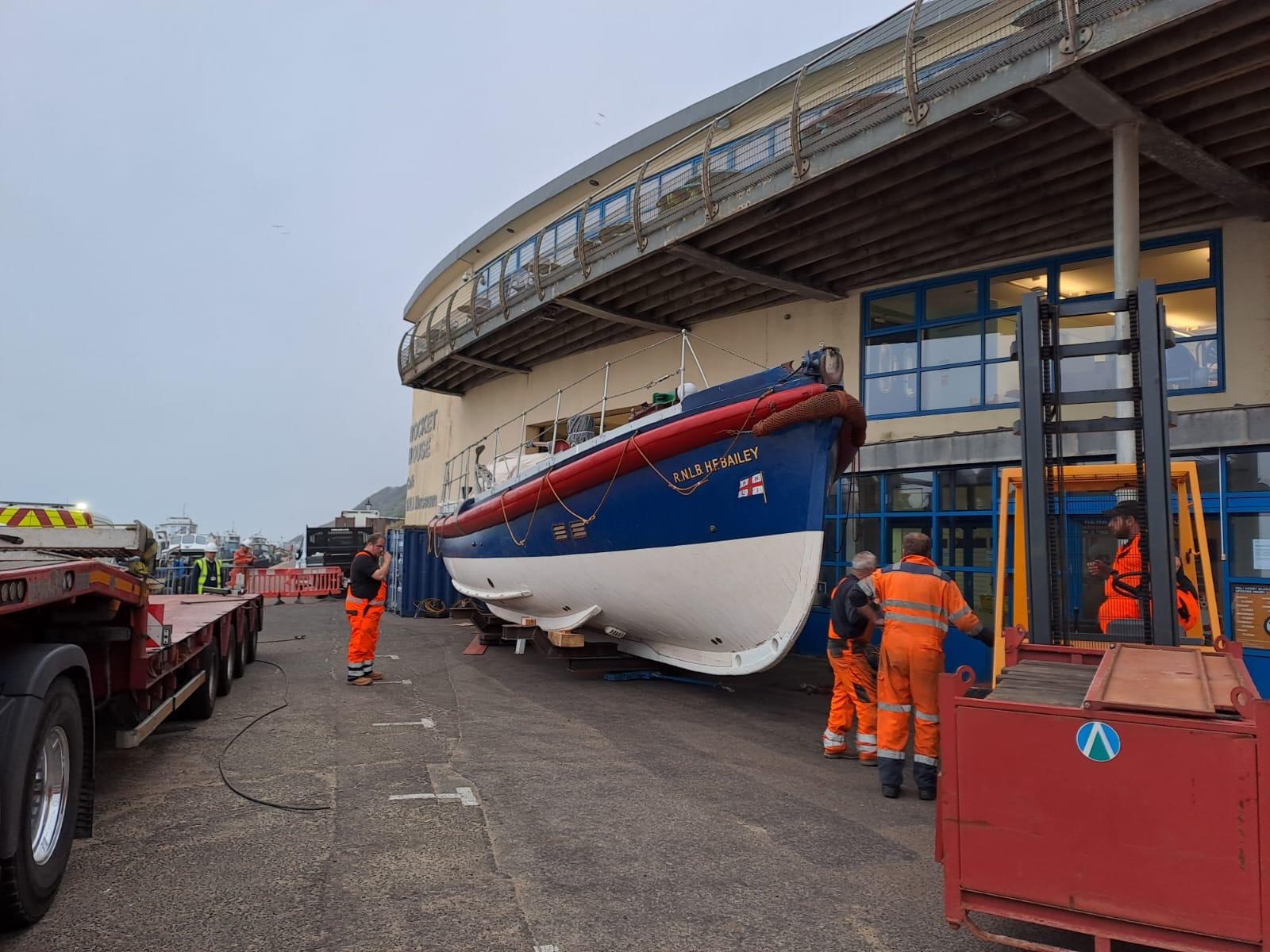 Workers in high vis workwear around RNLI heritage lifeboat in front of museum