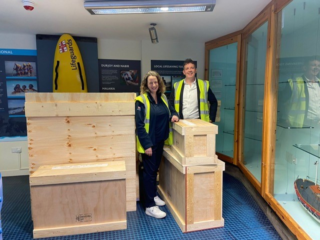 Two people in a Hi Vis vests next to wooden boxes.