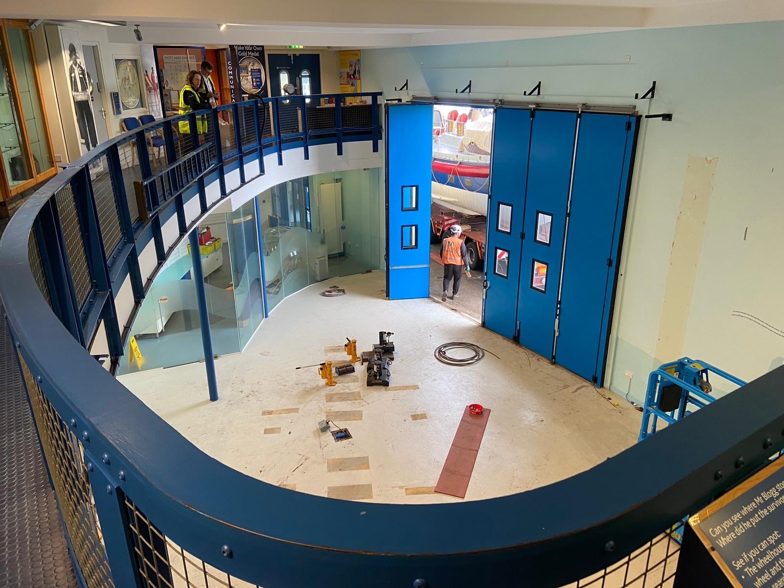 View of an empty museum room from balcony. Fencing of balcony stretches along the left side of the image.