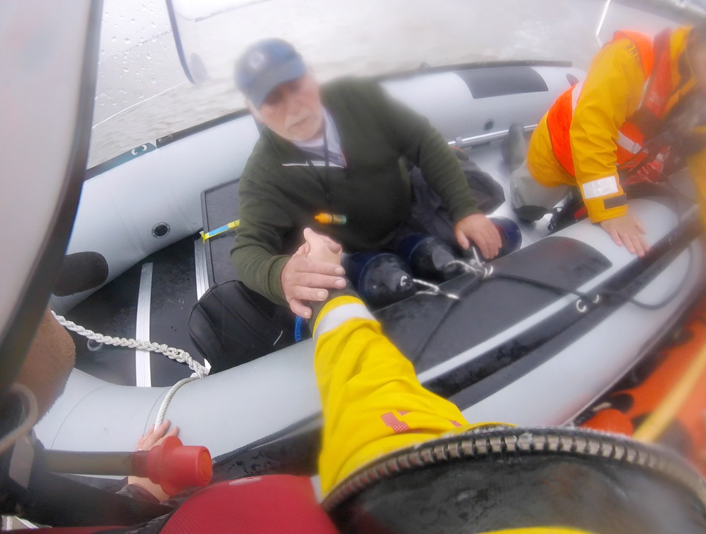 Allan being taken by the hand of lifeboat crew Simon Johnson from powerboat Salty Sea Dog