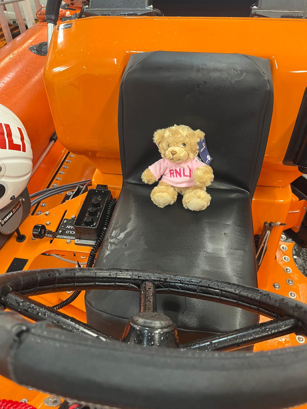 RNLI teddy bear in pink t-shirt sits on the helm seat on board the Atlantic-85 lifeboat.