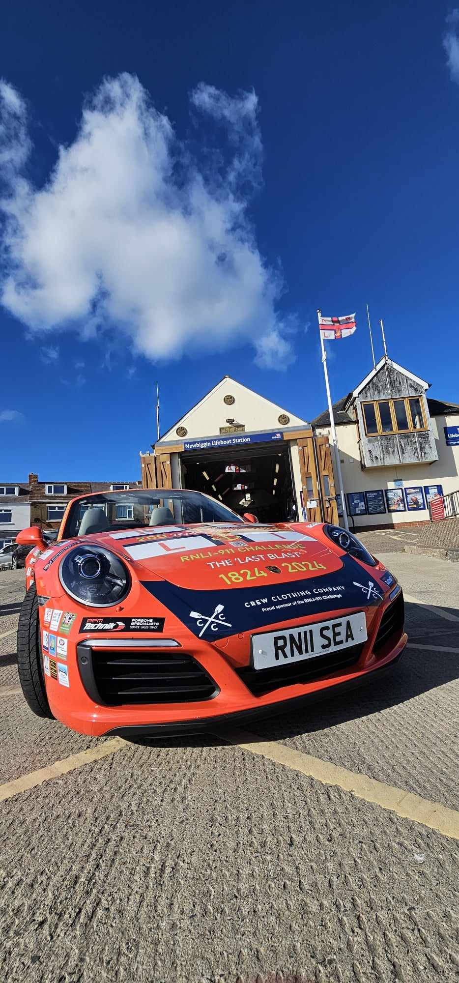 The eye catching Porsche 911 car in front of the boathouse.