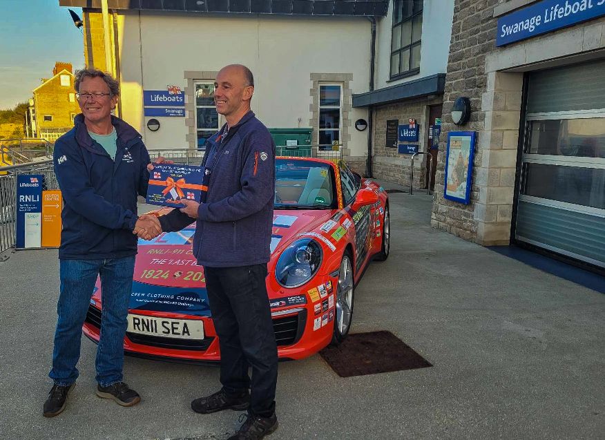 Lifeboat Opertations Manager Rob Pullman and Martin Coward from The Priory accepting the bespoke puzzle from Belinda and James
