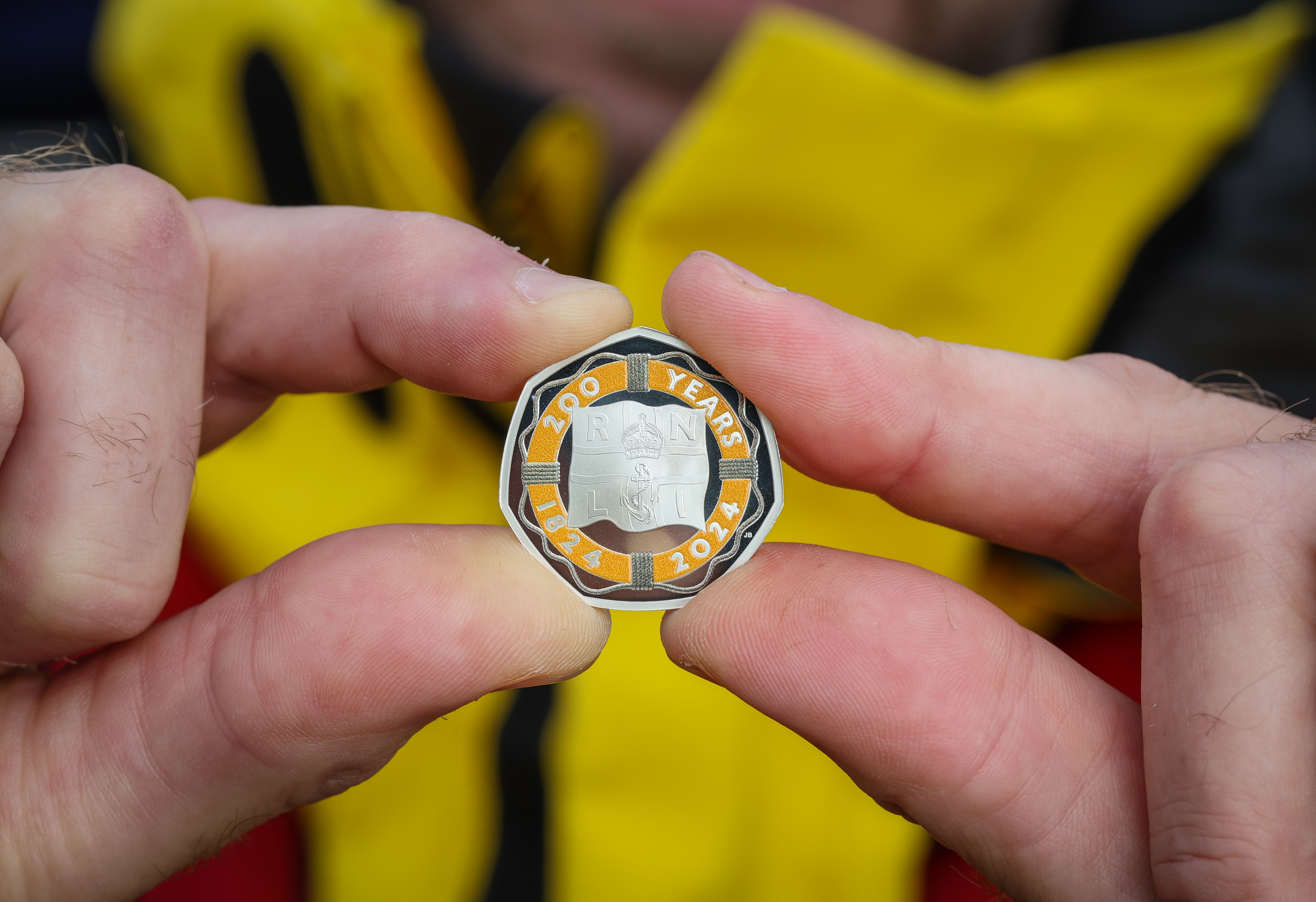 Close up of hands holding The Royal Mint commemorative RNLI 200 50p coin