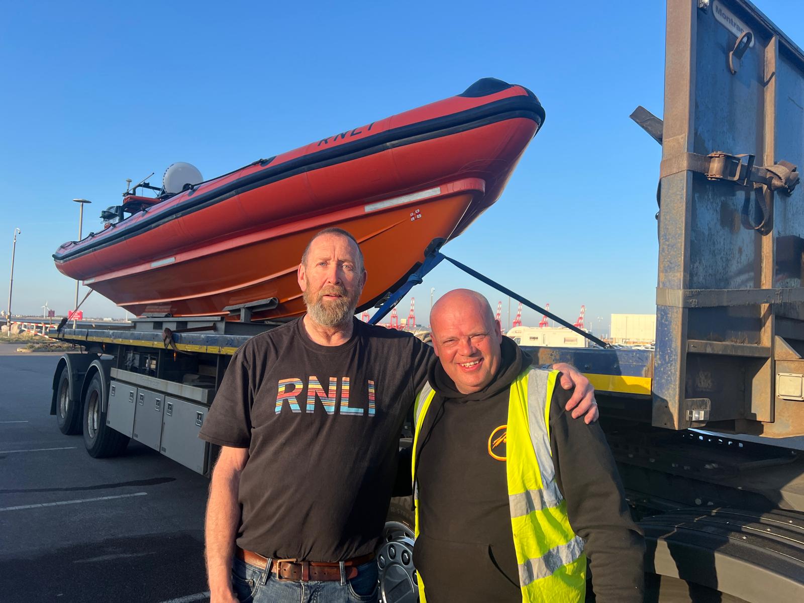Mike Jones and Jason pose in front of the relief craft, sat on the back of the flat bed transport truck.
