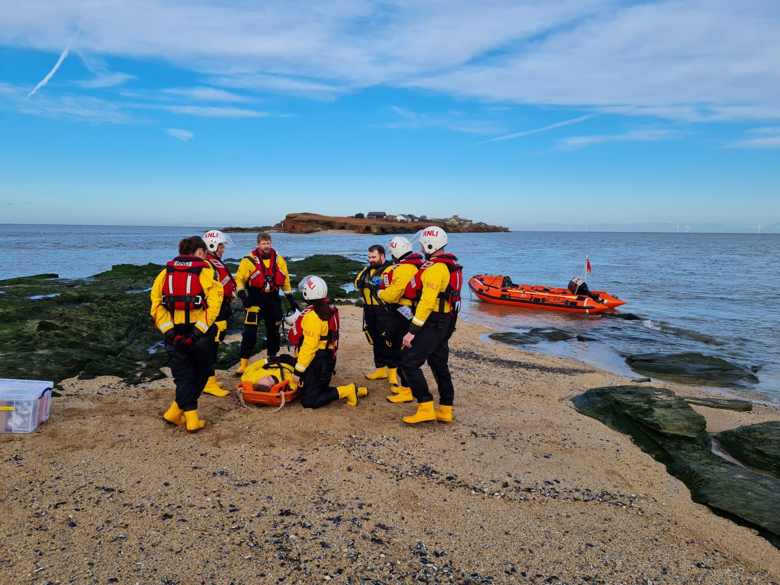 RNLI crew can be seen performing first aid training with the D class in the background