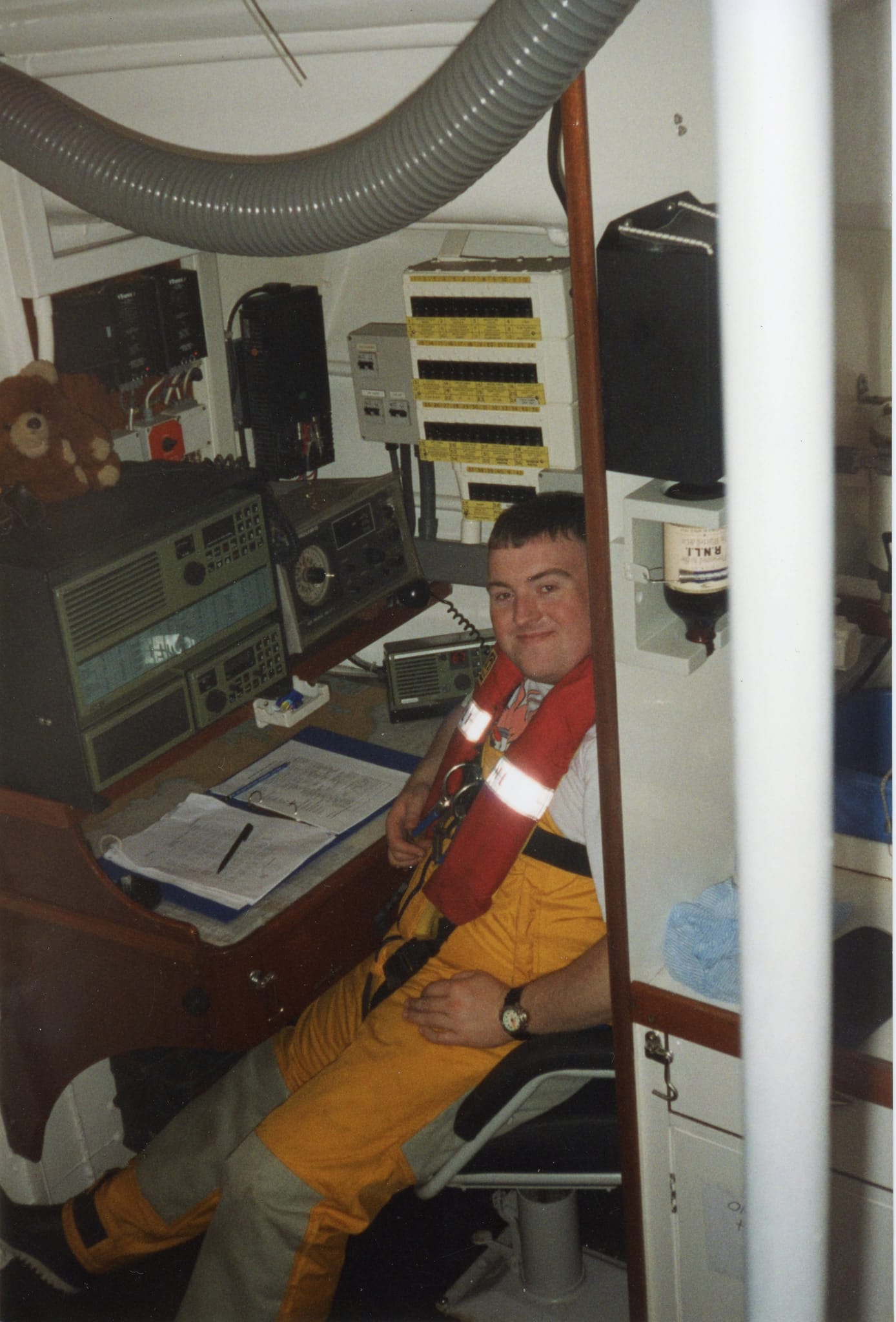 Andy WIlson, in his twenties, sitting at a desk. The communication logs are open in front of him, with radio equipment further back