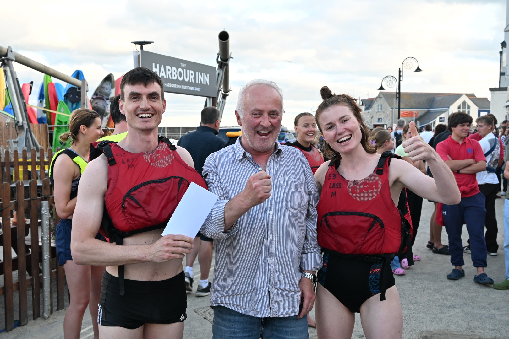 2 people in red tops receive prize from man in blue top