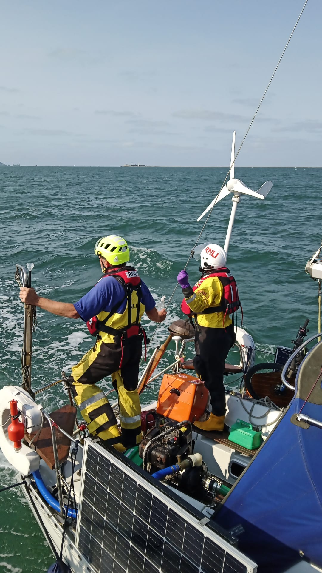 Two Yarmouth RNLI crew members are seen standing on the casualty vessel looking away from camera.