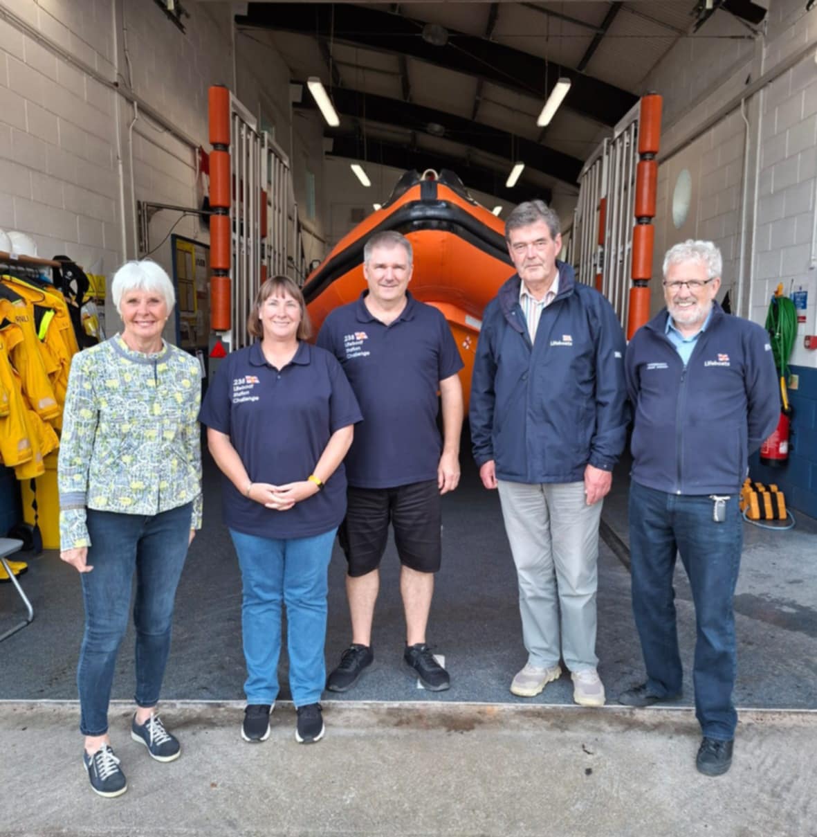 The visitors with RNLI volunteers with the inshore lifeboat James and Helen Mason