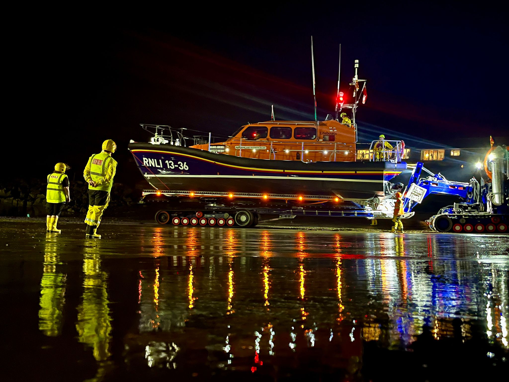 Seahouses RNLI responds to late-night medical emergency at sea Shannon class lifeboat launching in the dark. Crew members in full yellow RNLI kit in foreground
