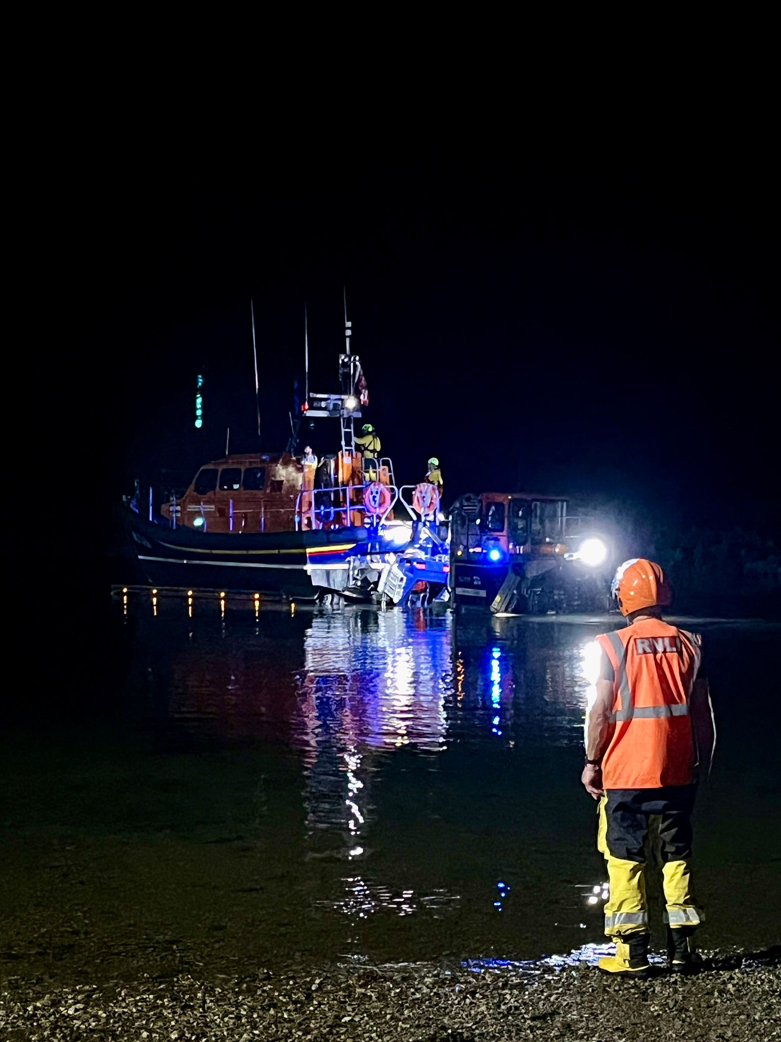 Seahouses RNLI responds to late-night medical emergency at sea Shannon class lifeboat launching in the dark. Crew members in full yellow RNLI kit in foreground
