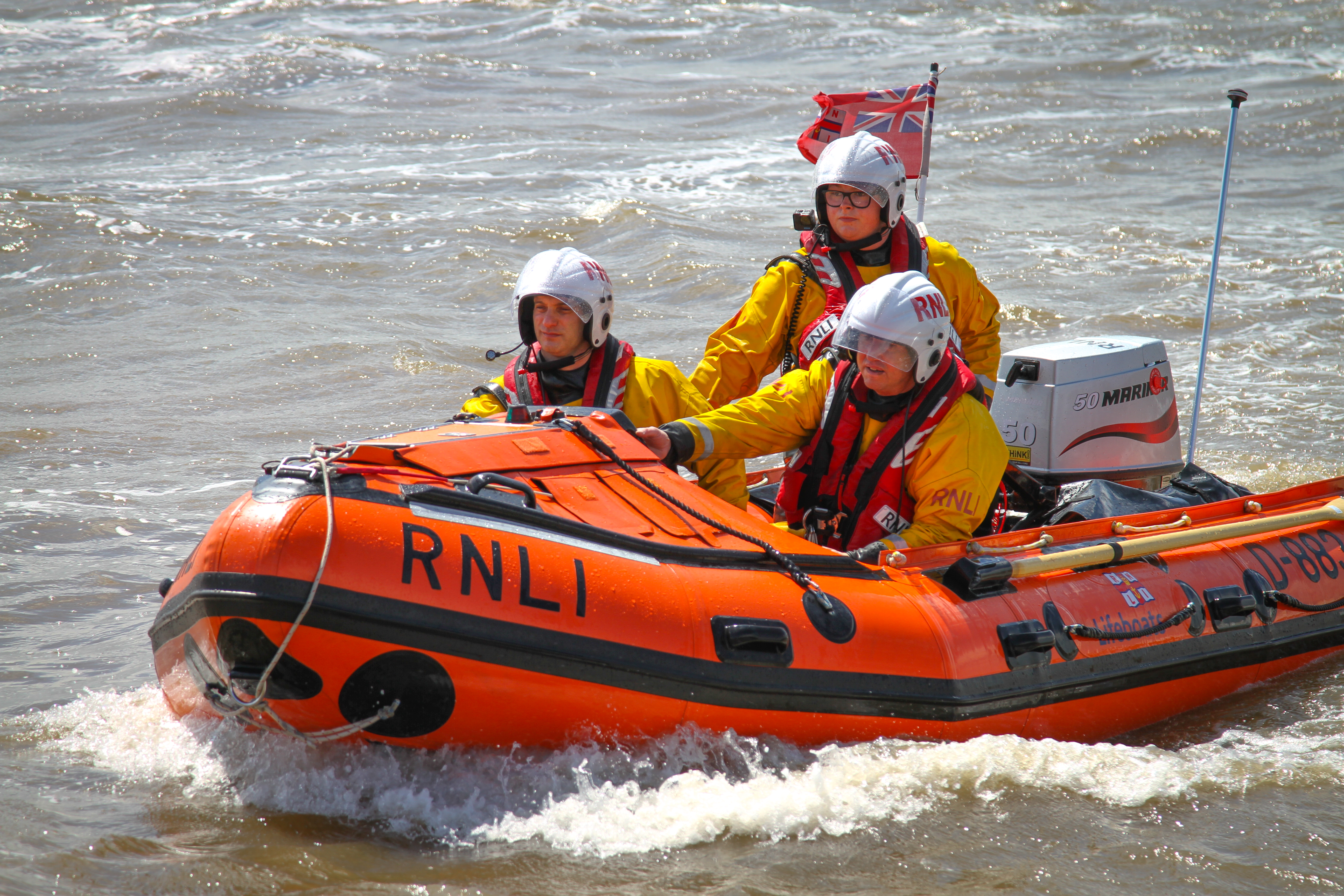 The D class lifeboat can be seen in the water with three crew within it looking forward.