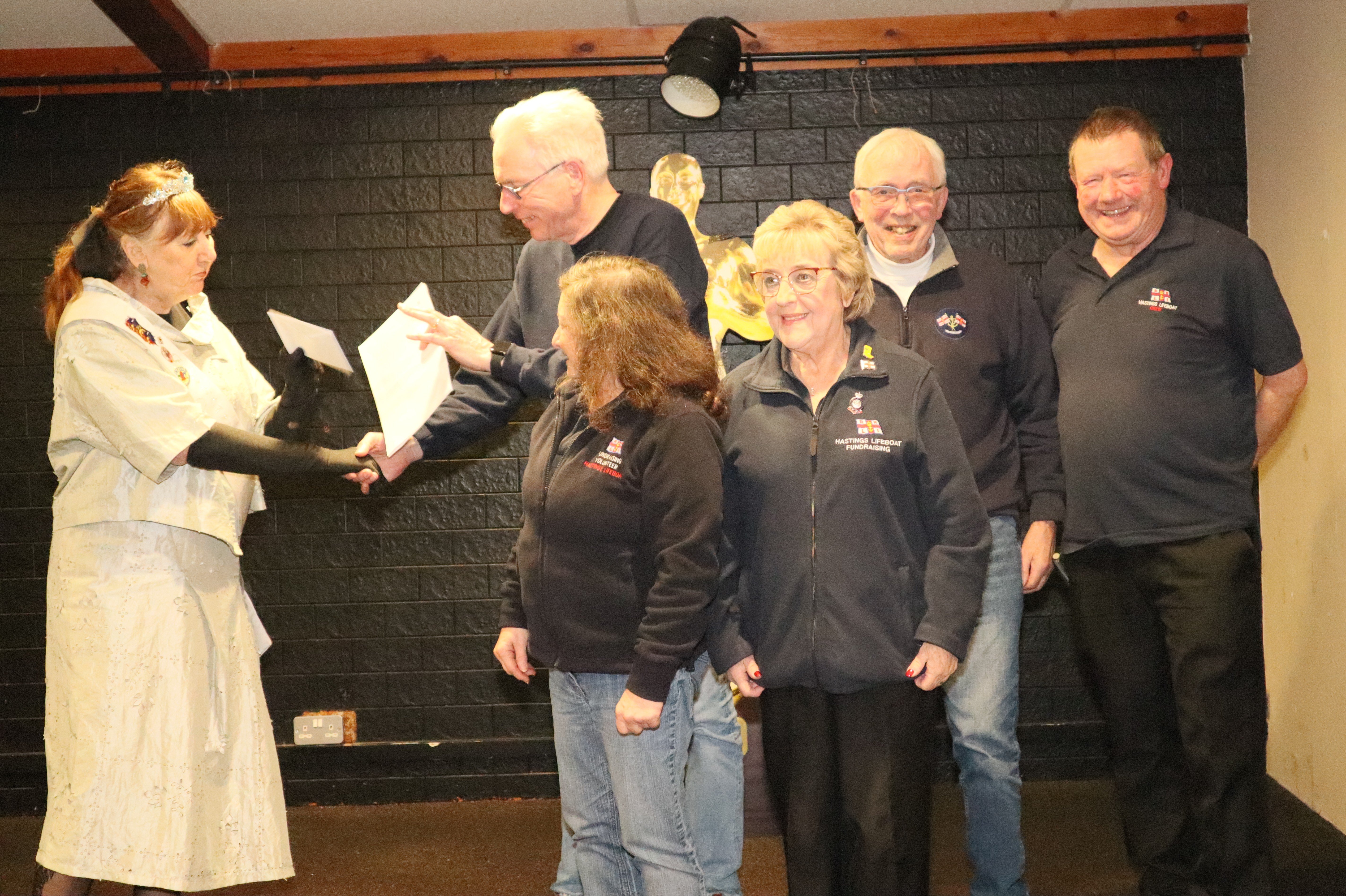 Bob Morrison, with other Hastings RNLI volunteers standing alongside him, is presented with a cheque
