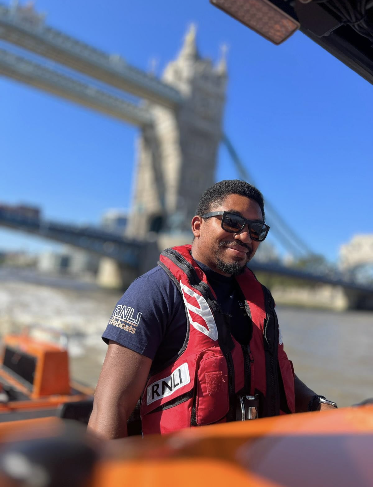 Storm on the helm wearing sunglasses with Tower Bridge in background on the River Thames.