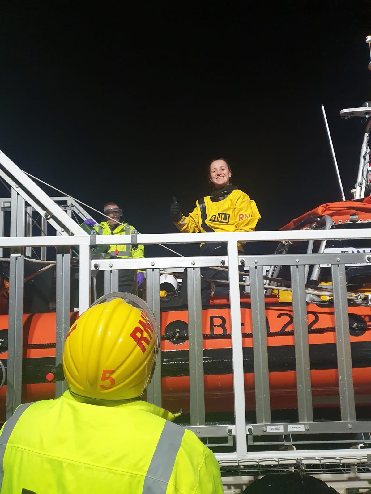A smiling Mihaela Simeonova looking down from a large orange lifeboat after her first afloat shout