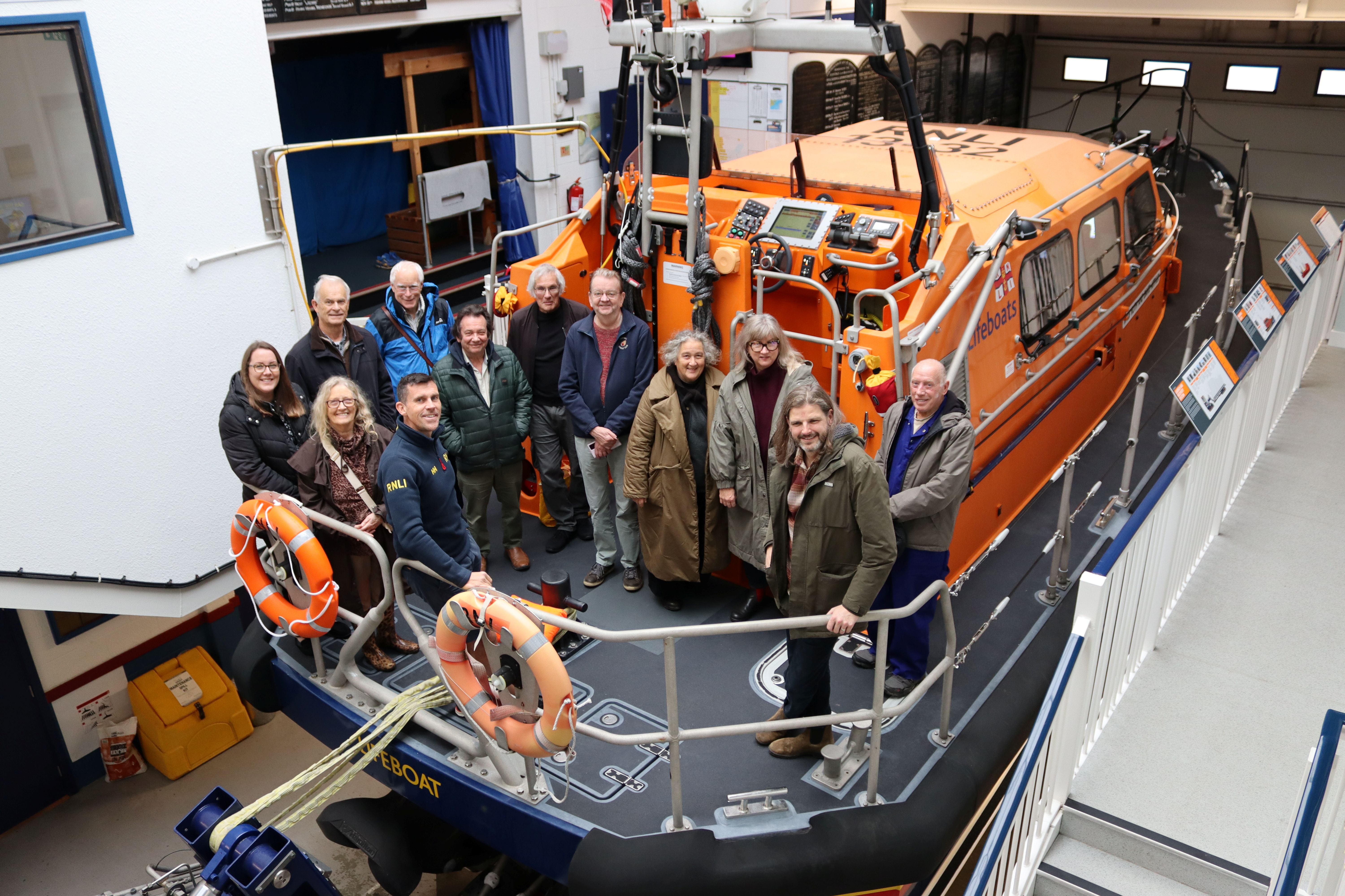Members of Hastings Coastal Users Group standing on the relief Shannon lifeboat Ruth and David Arthur in Hastings lifeboat station