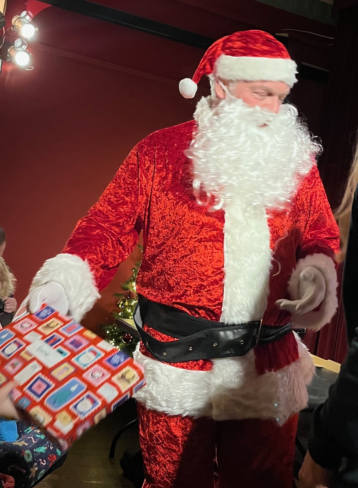 Santa handing out a well wrapped Christmas gift 