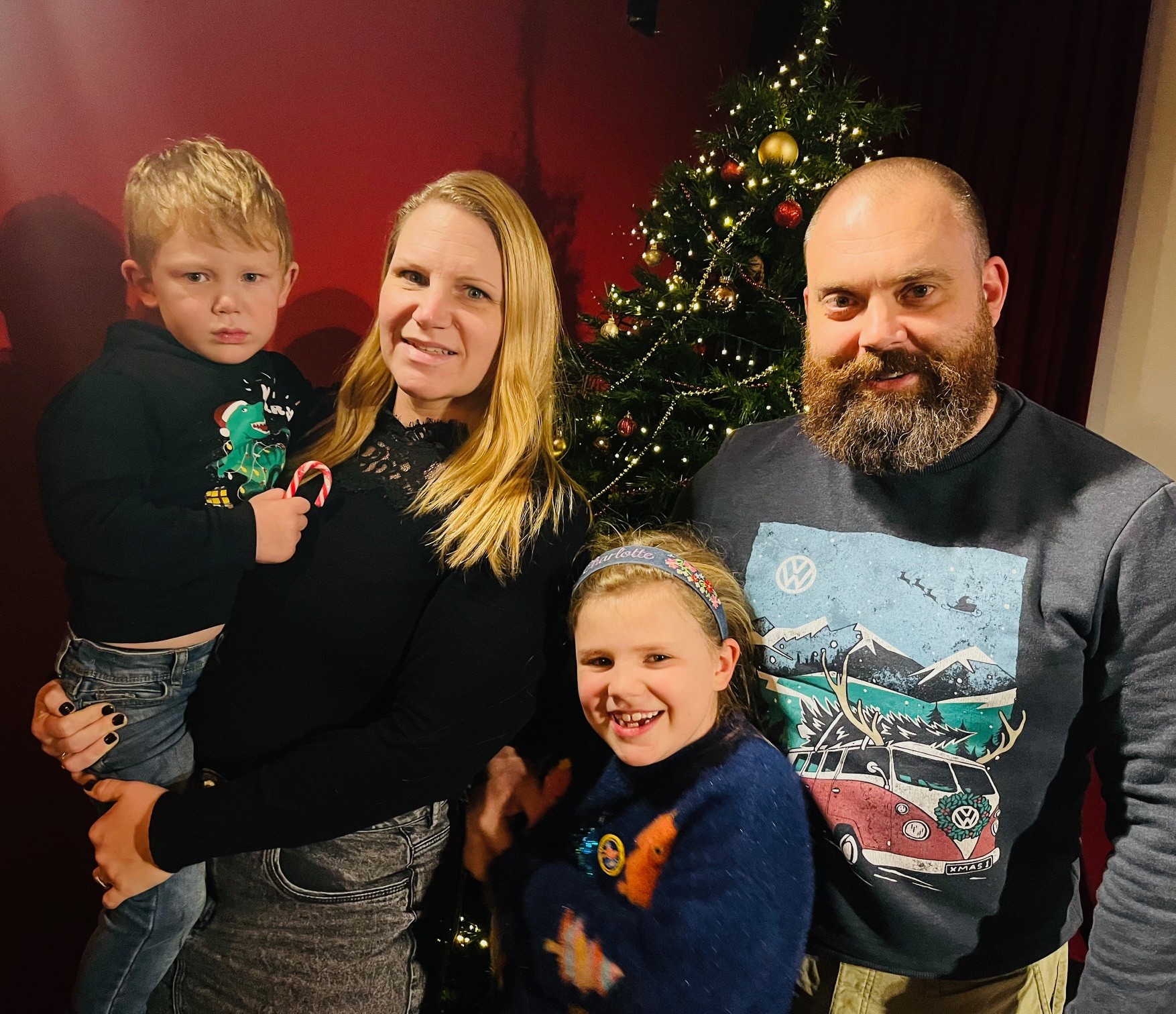 A family of four in front of a Christmas tree