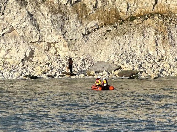 Y boat in front white cliffs with casualty on rocks with crew in full RNLI yellow kit