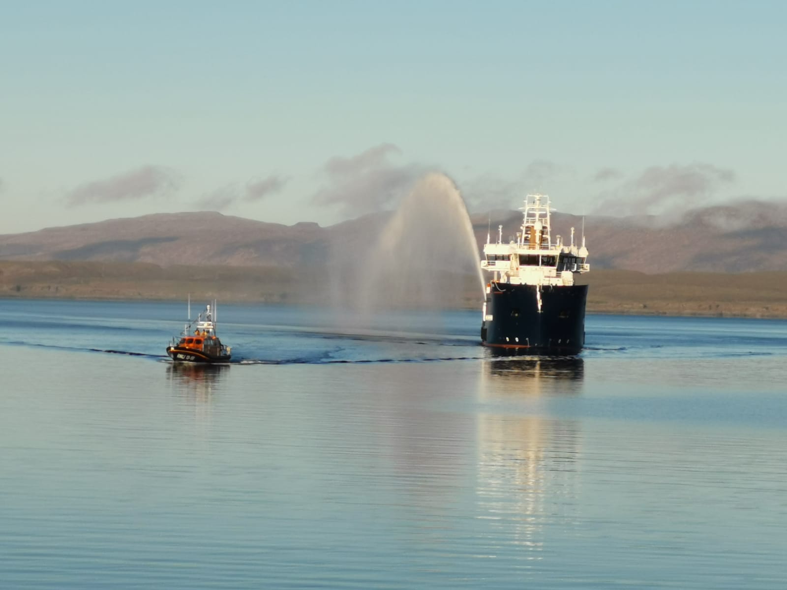 A photo taken from the shore of Oban's Shannon class lifeboat leading the Pole Star into Oban Bay.