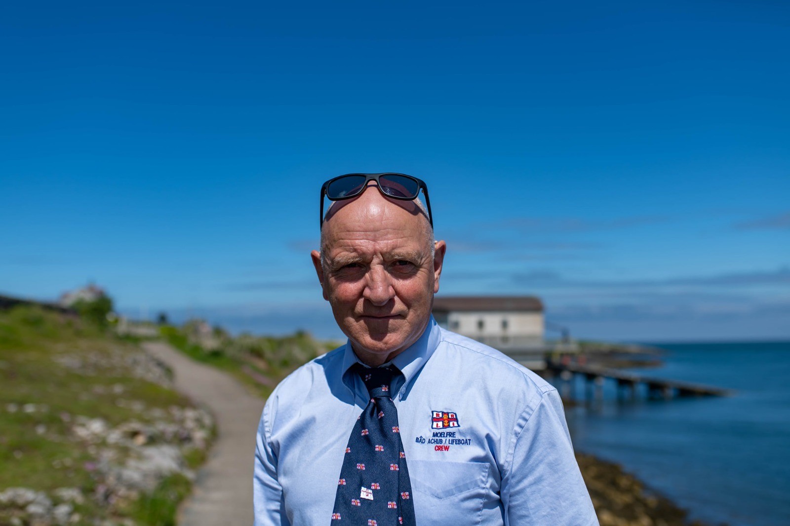 RNLI Moelfre volunteer Phil Williams standing with the sea behind him