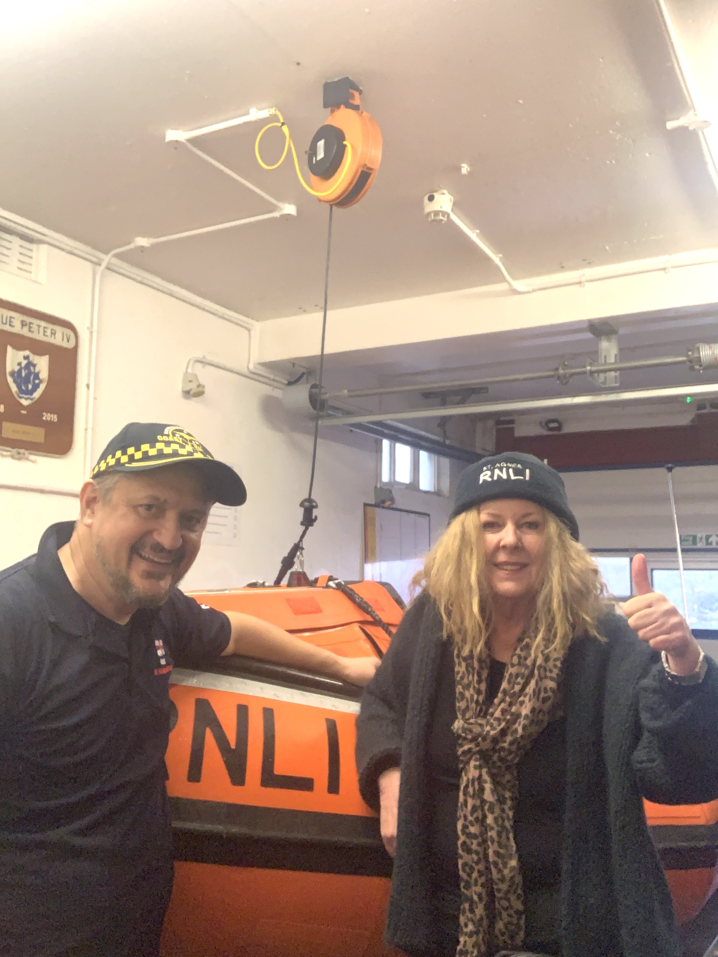 Volunteers from Cornwall and Australia stand in front of orange D Class lifeboat.